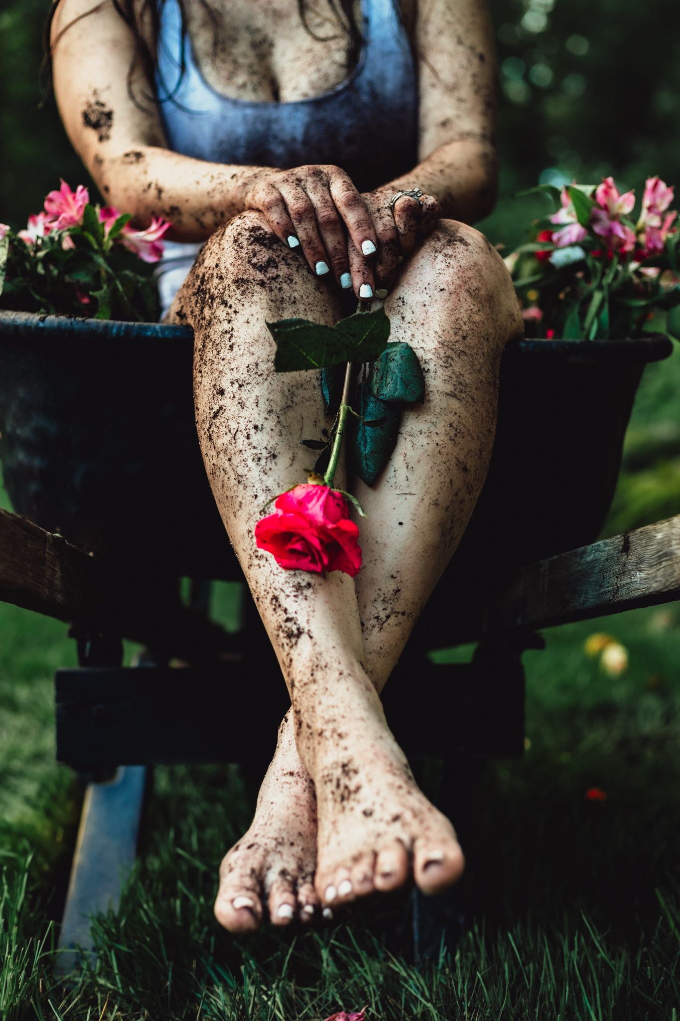 woman in wheelbarrow holding flower, emotional, raining, garden, dramatic, lifestyle, creative photoshoot, themed