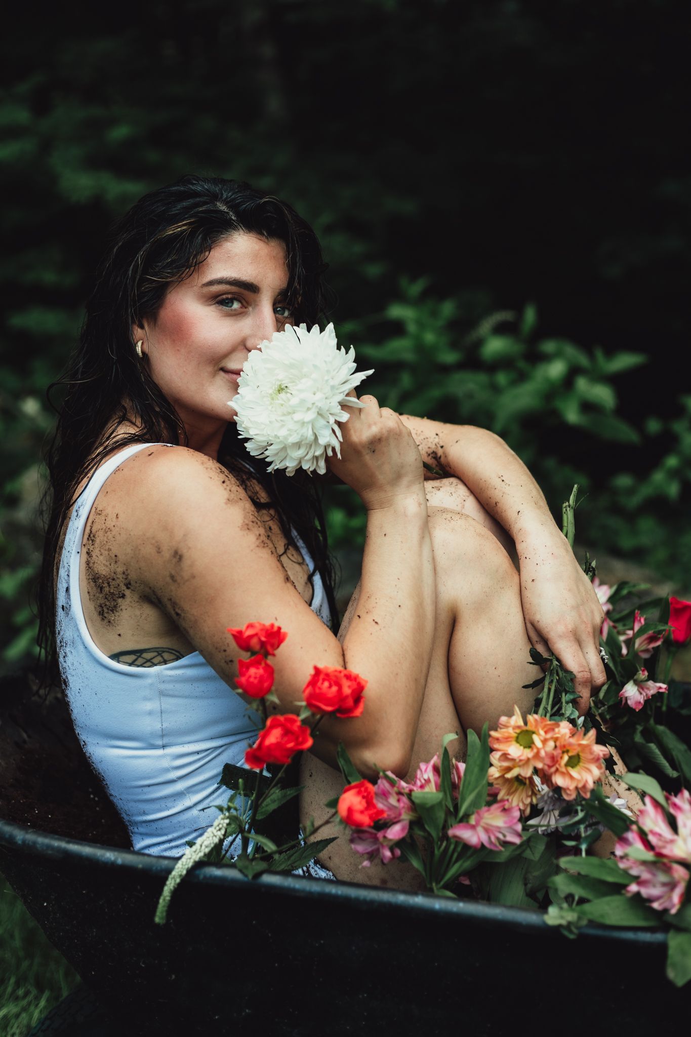 woman in wheelbarrow holding flower, emotional, raining, garden, dramatic, lifestyle, creative photoshoot, themed