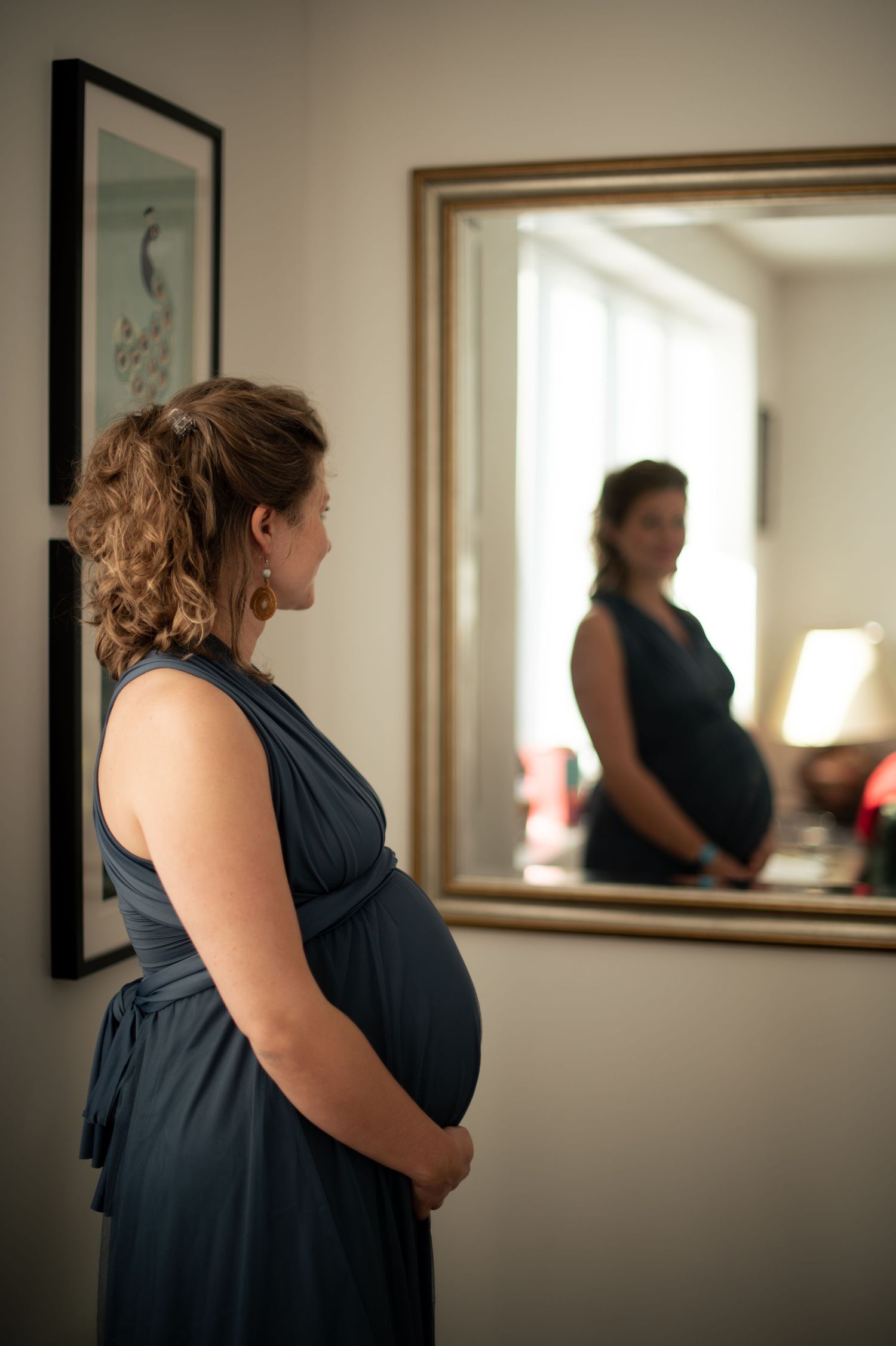 Artistic mirror portrait of a pregnant woman during an indoor maternity shoot.