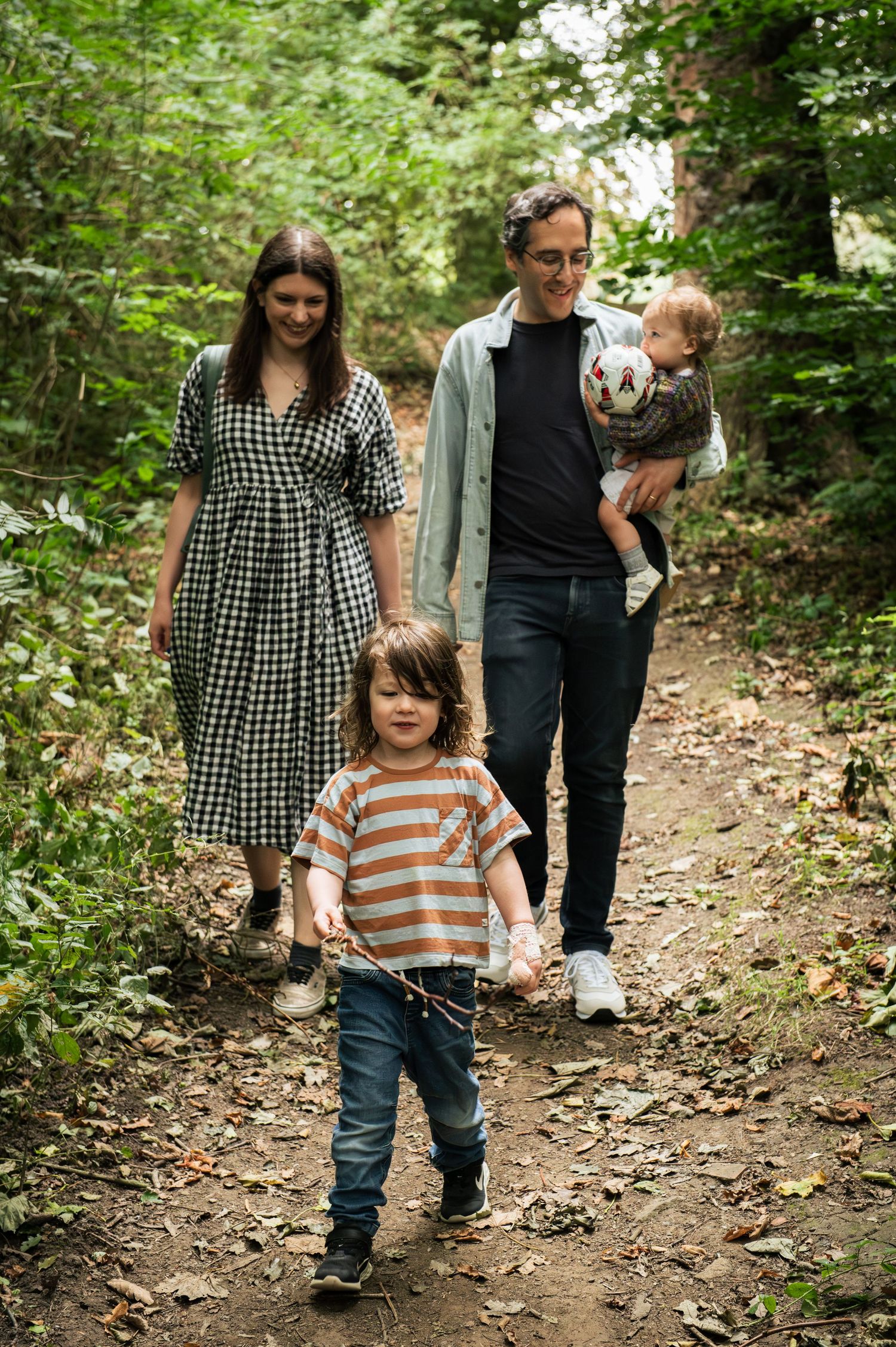 Family walking together on a wooded trail in Leeds, during a casual outdoor photo session.