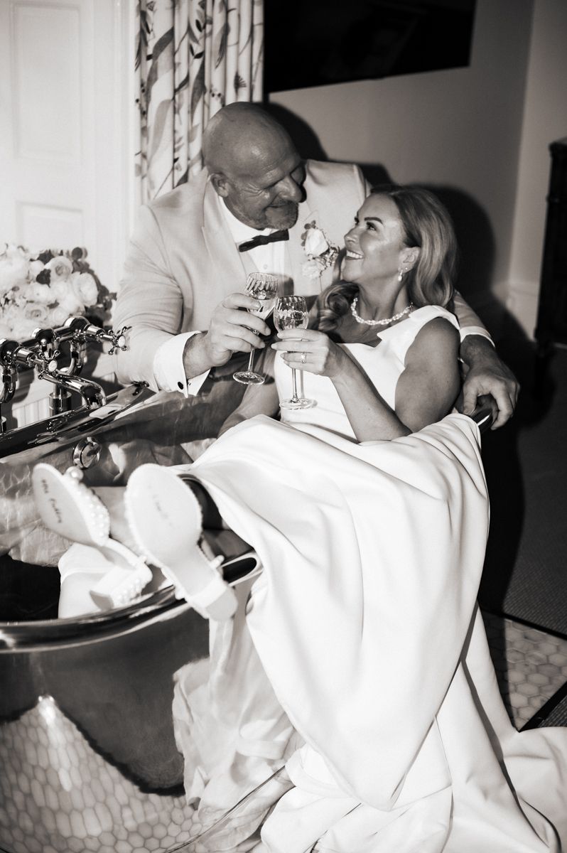 Black and white high-flash photo of a couple sharing drinks in a bathtub at their wedding reception at Wentbridge House Hotel, Pontefract.