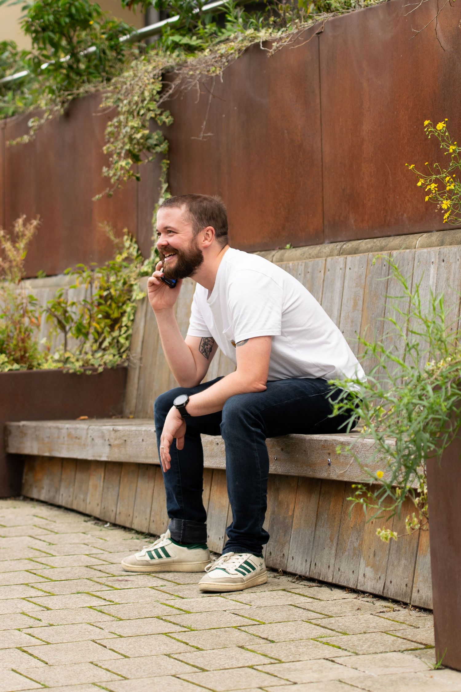 Person sitting on wooden bench against rustic metal wall, accompanying business photo for a Leeds marketing business.