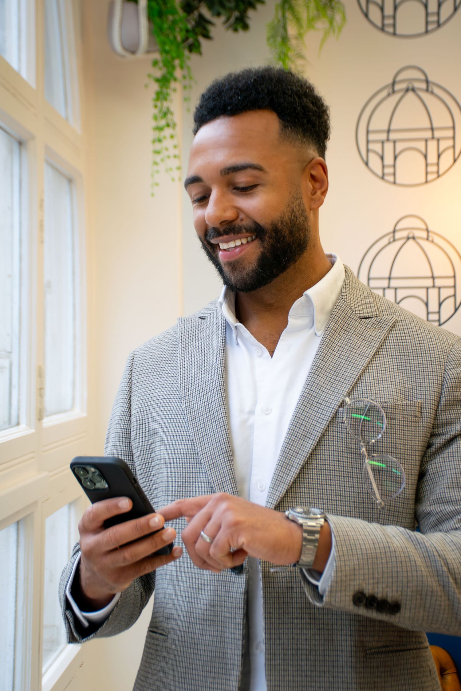 Business person in grey blazer and white shirt looking at mobile phone in a relaxed business headshot for Leeds marketing business.