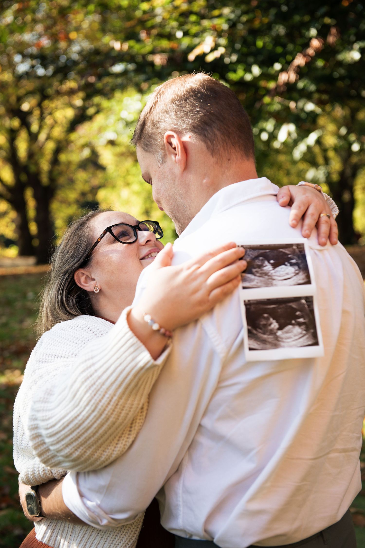 A couple sharing a tender moment to announce their pregnancy during a photoshoot in Roundhay Park, Leeds.