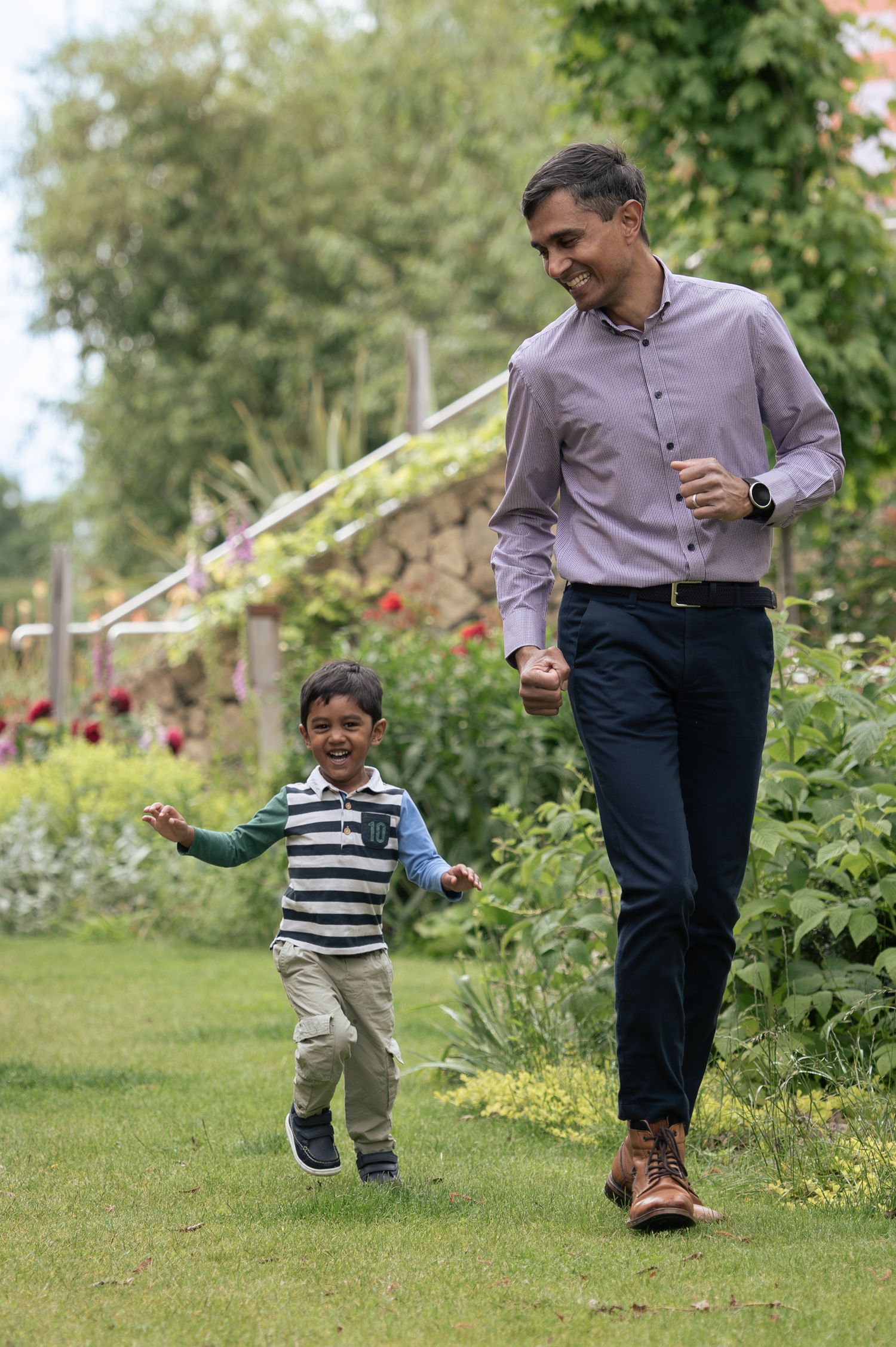 Family photography of a father and son in Leeds, playing in a garden with flowers and greenery.