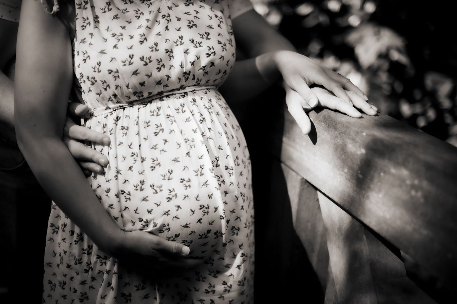 Black and white detail shot of a couple embracing their bump during a maternity session.