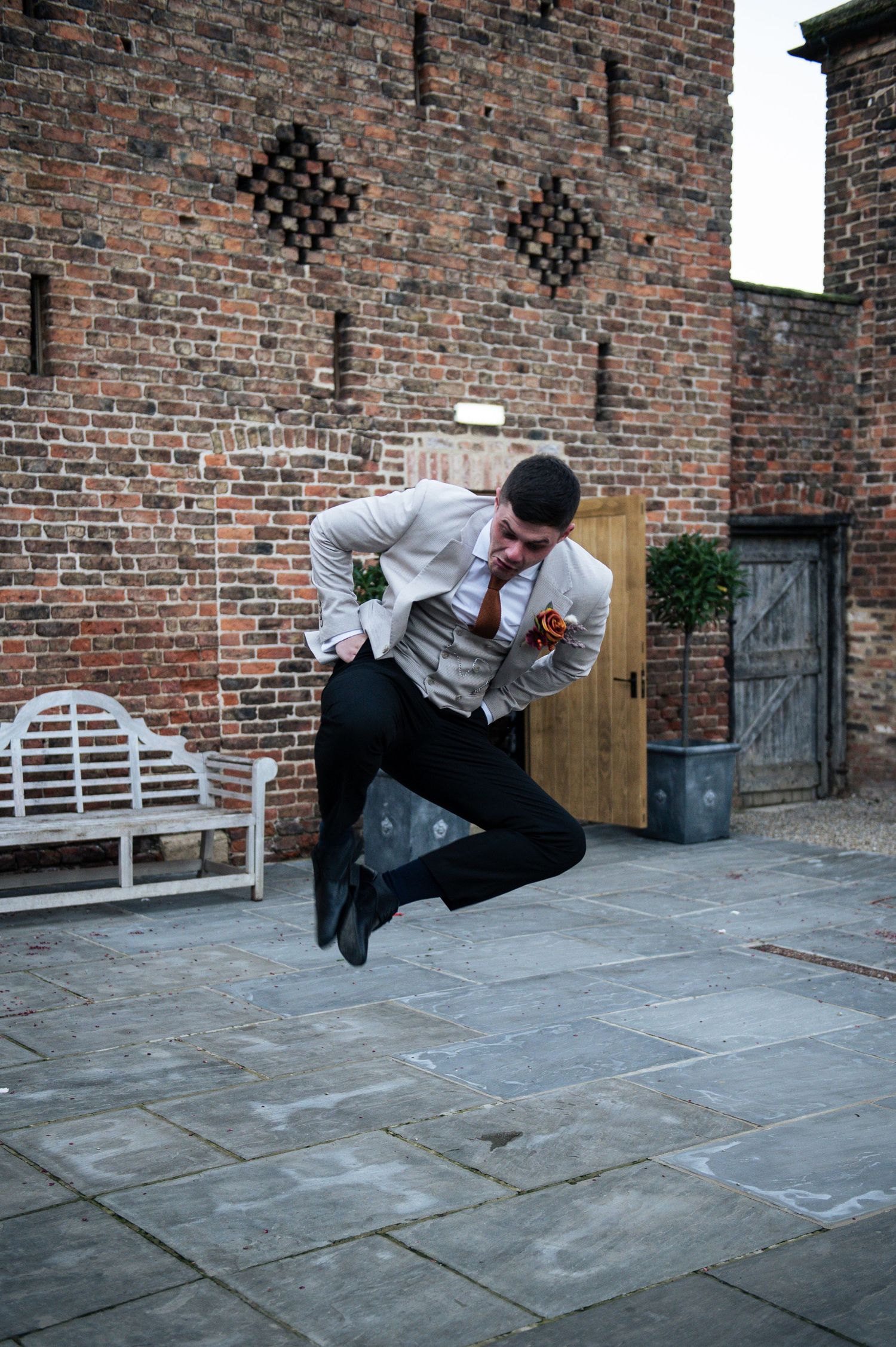 A sequence showing a person performing an impressive sideways jump against a brick wall background, at Lodge Farm Weddings, Yorkshire.