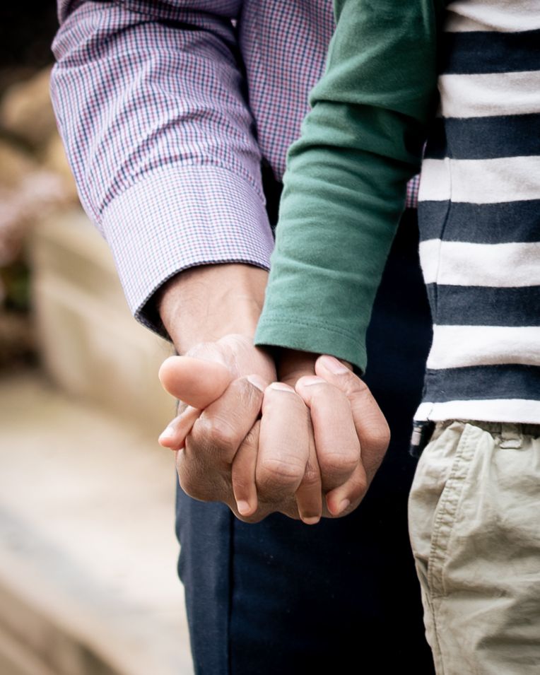 Close-up family photos of a father and son holding hands during an intimate family moment, in Leeds, West Yorkshire.