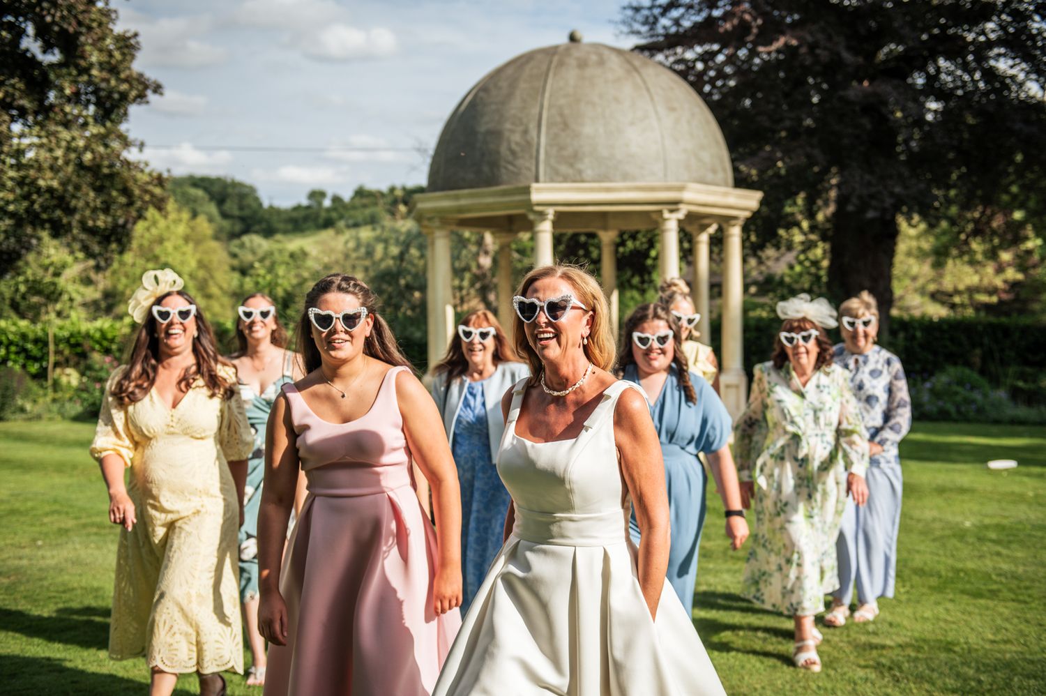 Bridesmaids and bride don heart sunglasses, looking great in pastel dresses under a sunny sky at Wentbridge House Hotel, Pontefract.