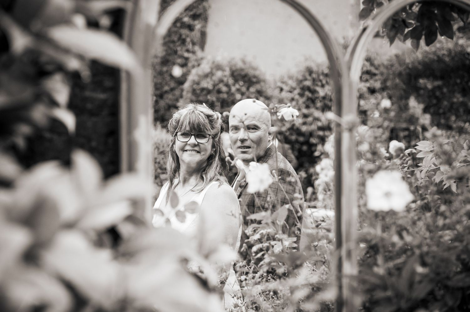 A bride and groom pose in the garden of Holdsworth House, Yorkshire, for an artistic floral wedding portrait.