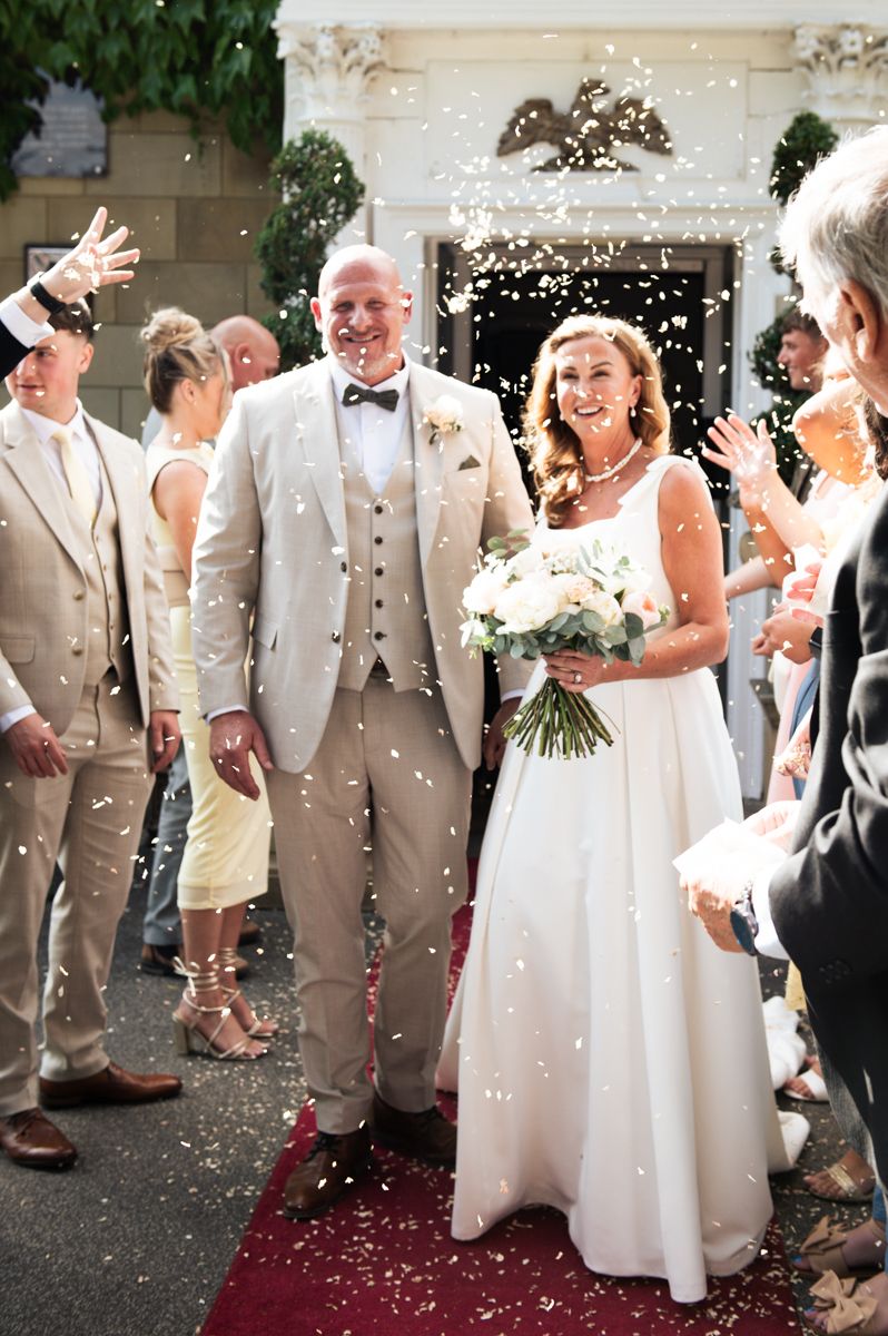 Wedding celebration at Wentbridge House Hotel, Pontefract, with confetti shower as couple walks through crowd in formal attire.
