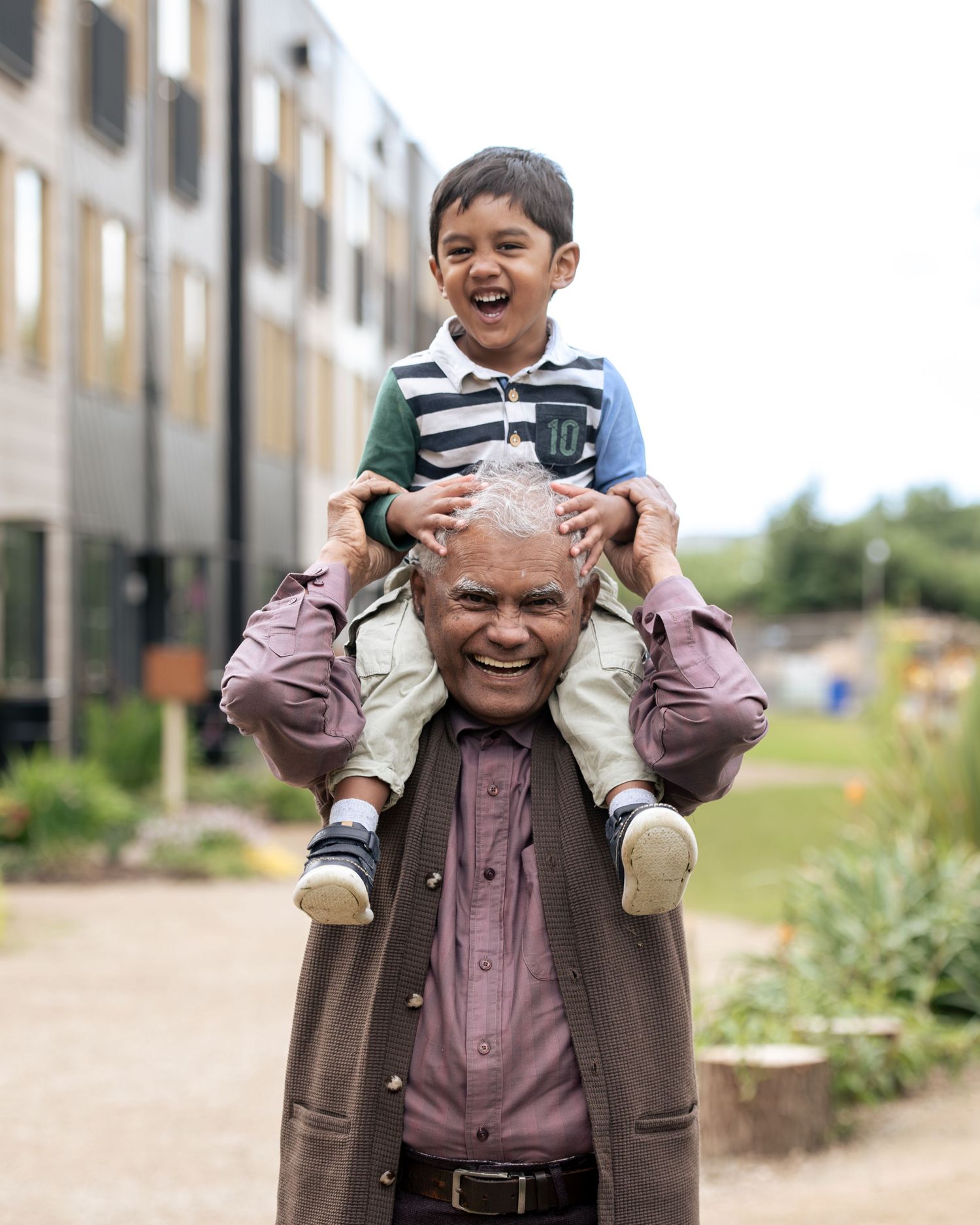 A playful piggyback ride from grandpa, showing joyful outdoor moments on a sunny day, during a family photoshoot in Leeds.