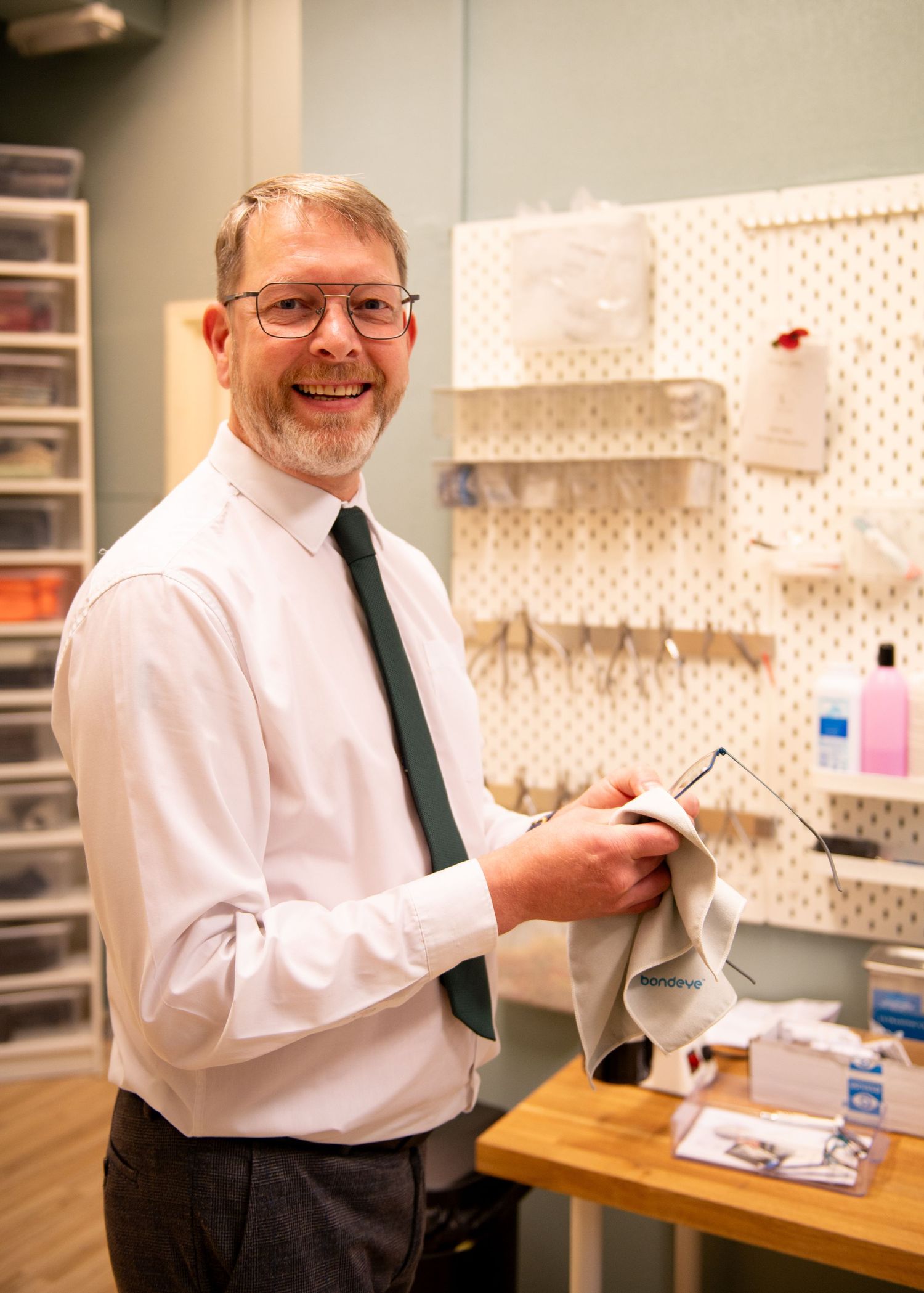 Optometrist in white shirt and tie working in optical lab storage area - business photos in Brigg, North Lincolnshire.