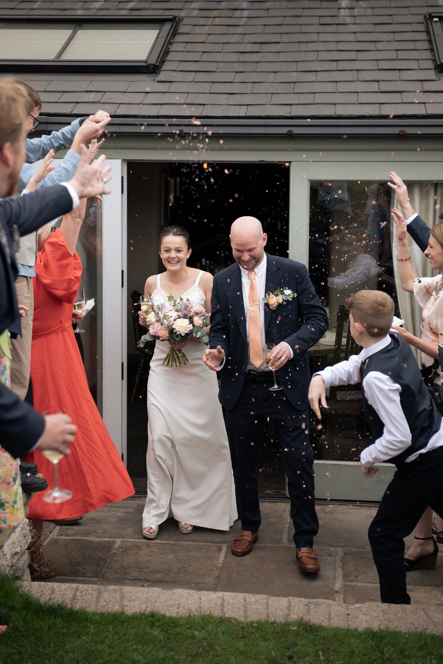 Wedding party jumping in celebration during a confetti tunnel at a wedding reception at The Blind Bull Inn, Buxton.