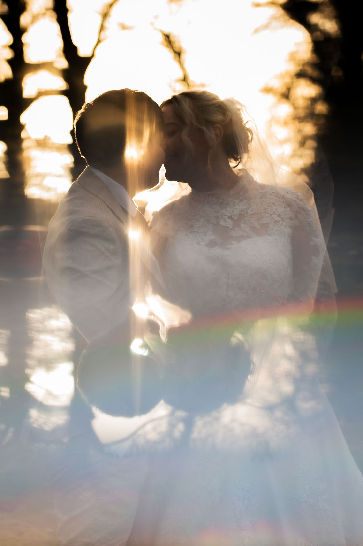 Romantic sunset silhouette of LGBT / lesbian newlyweds with lens flare and rainbow effect at Lodge Farm Weddings, Yorkshire.