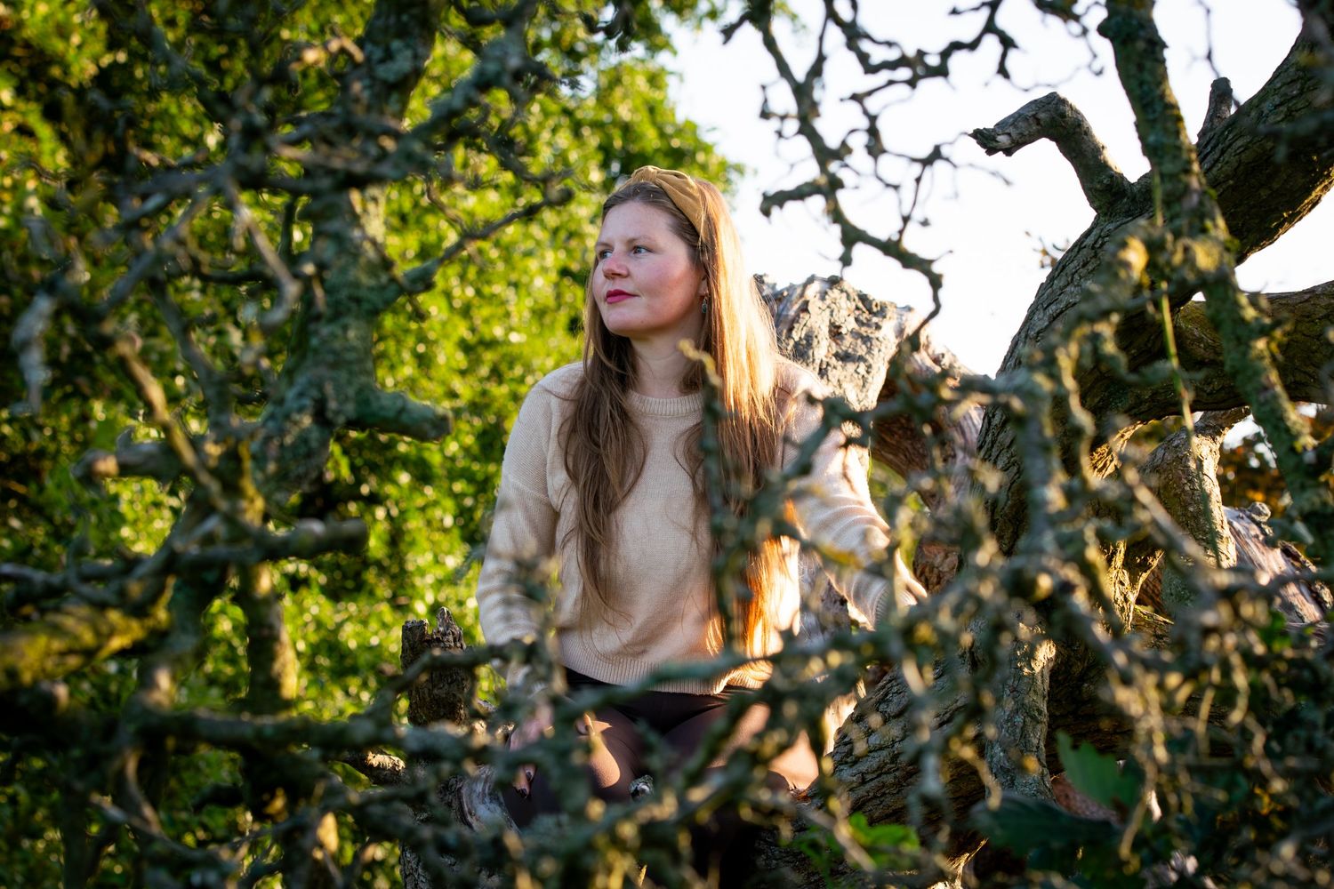 A natural outdoor portrait among tree branches in golden sunlight, for a Northumbria-based yoga teacher.