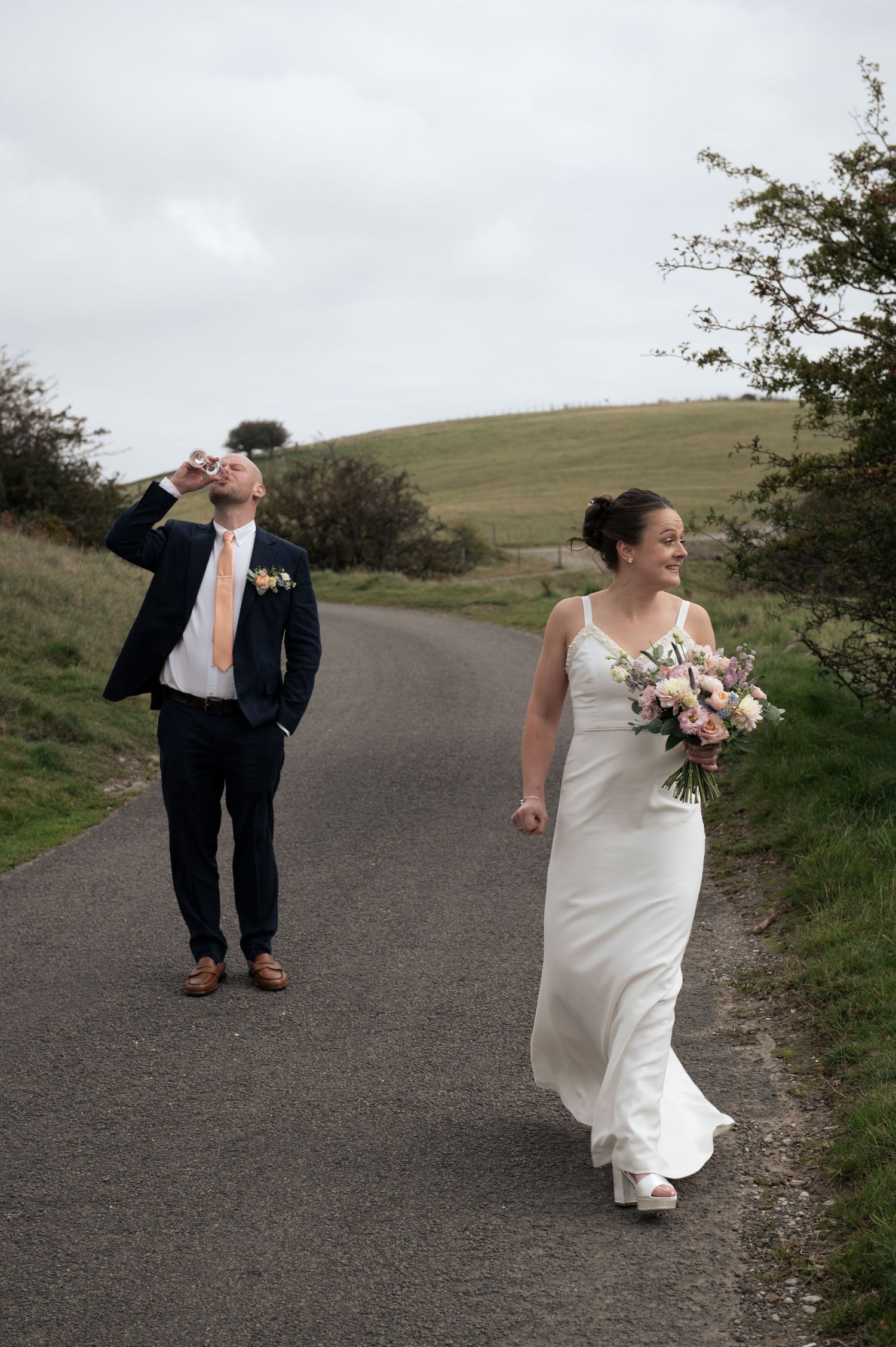 Wedding couple walking casually drinking champagne on Longley Edge, Buxton.