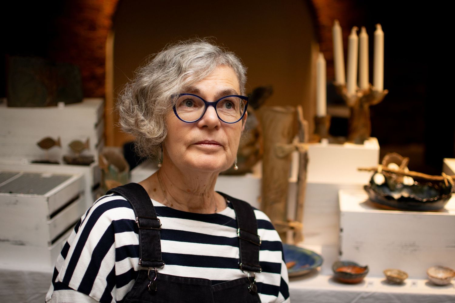 Business owner in front of her pottery in a warmly lit interior space in the Corn Exchange, Leeds.
