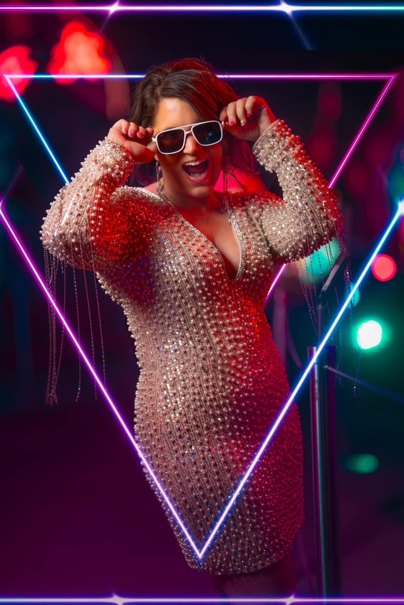 Photo of Sheena, owner of Moments De La Vie Photography, pictured here  in a peal embellished dress with white Sunglasses at Neon Museum