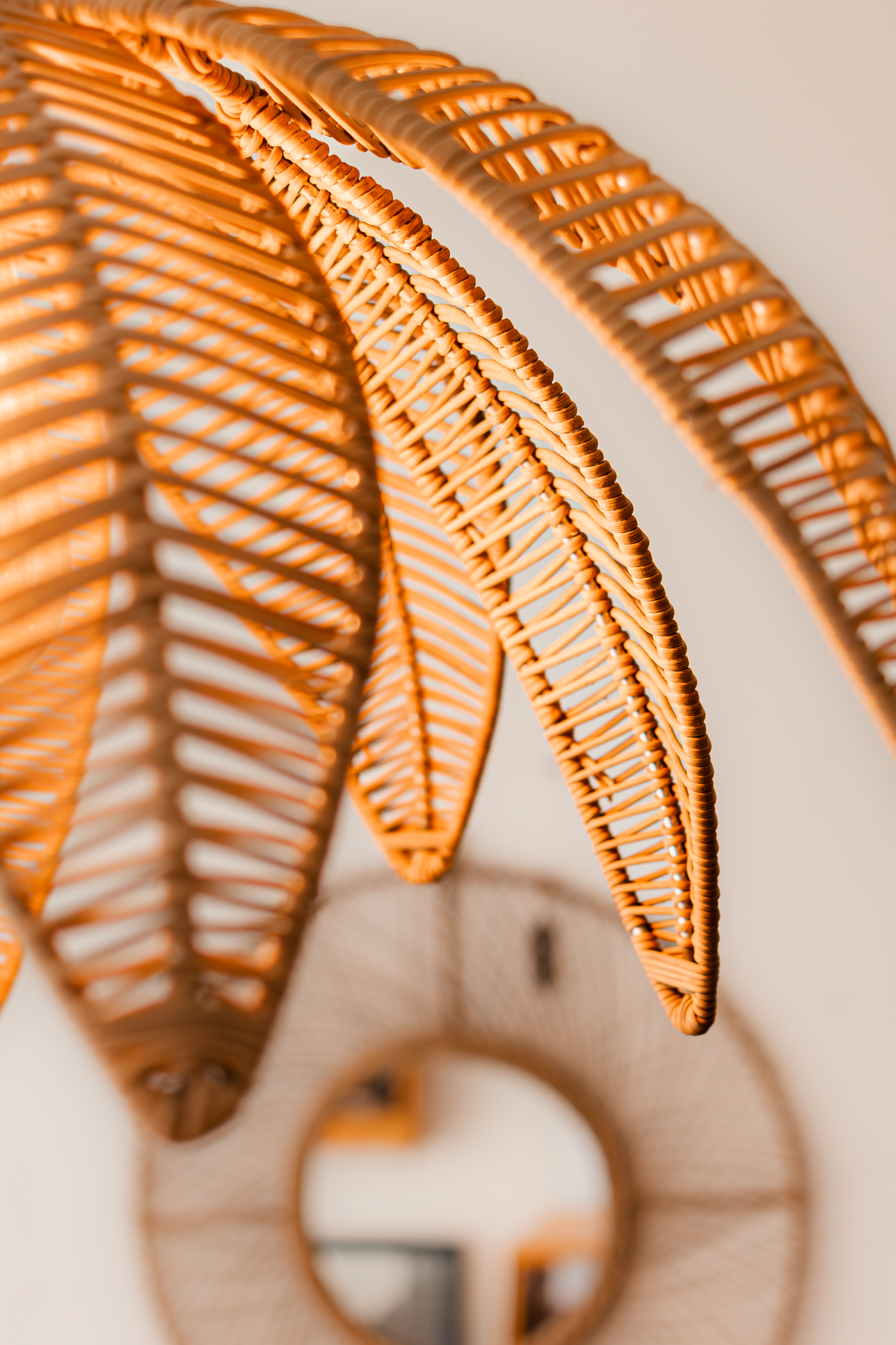 Close-up of woven rattan pendant lamp showing intricate geometric pattern and mirror reflection.