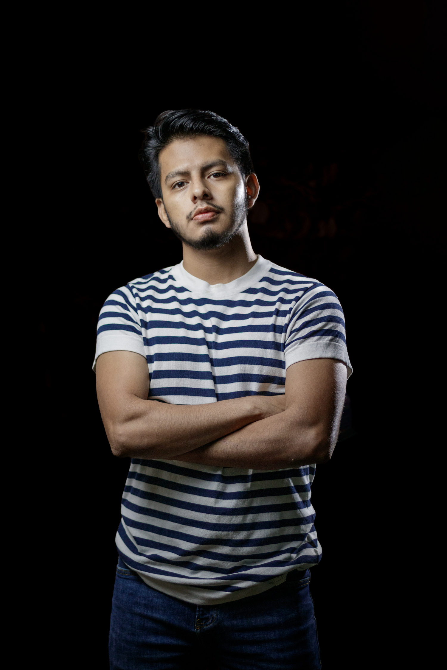 Person wearing blue and white striped t-shirt posing against dark background.