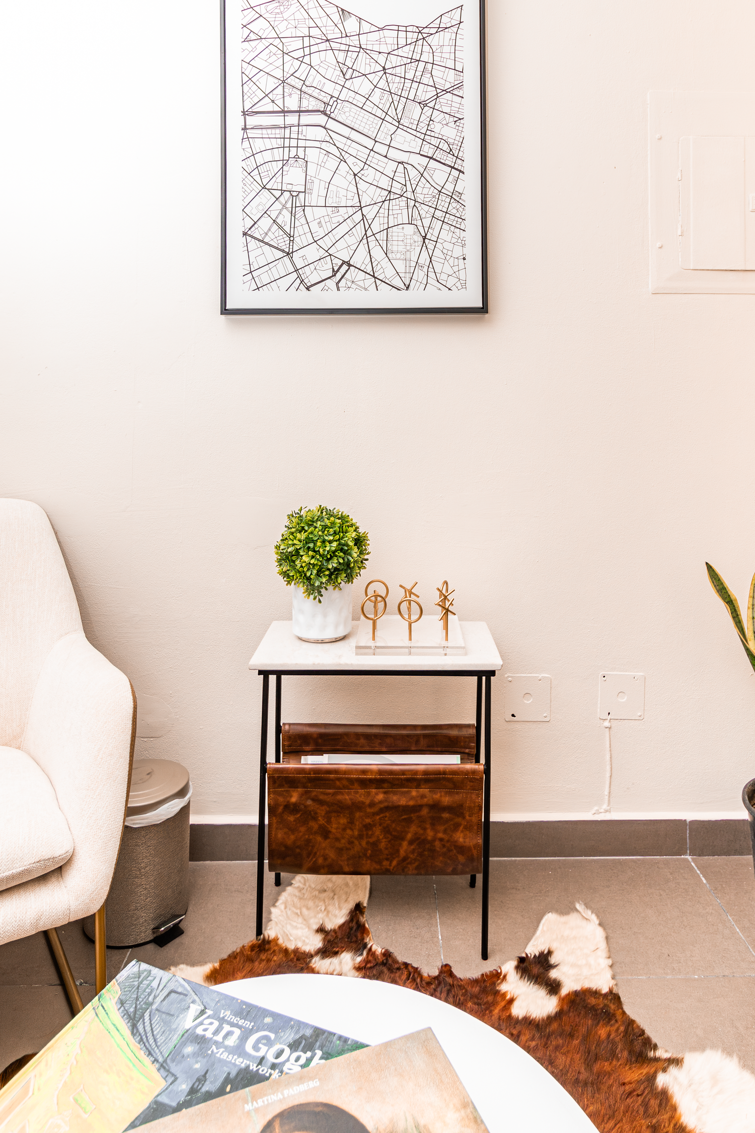 Minimalist corner featuring side table, map artwork and decorative plants.