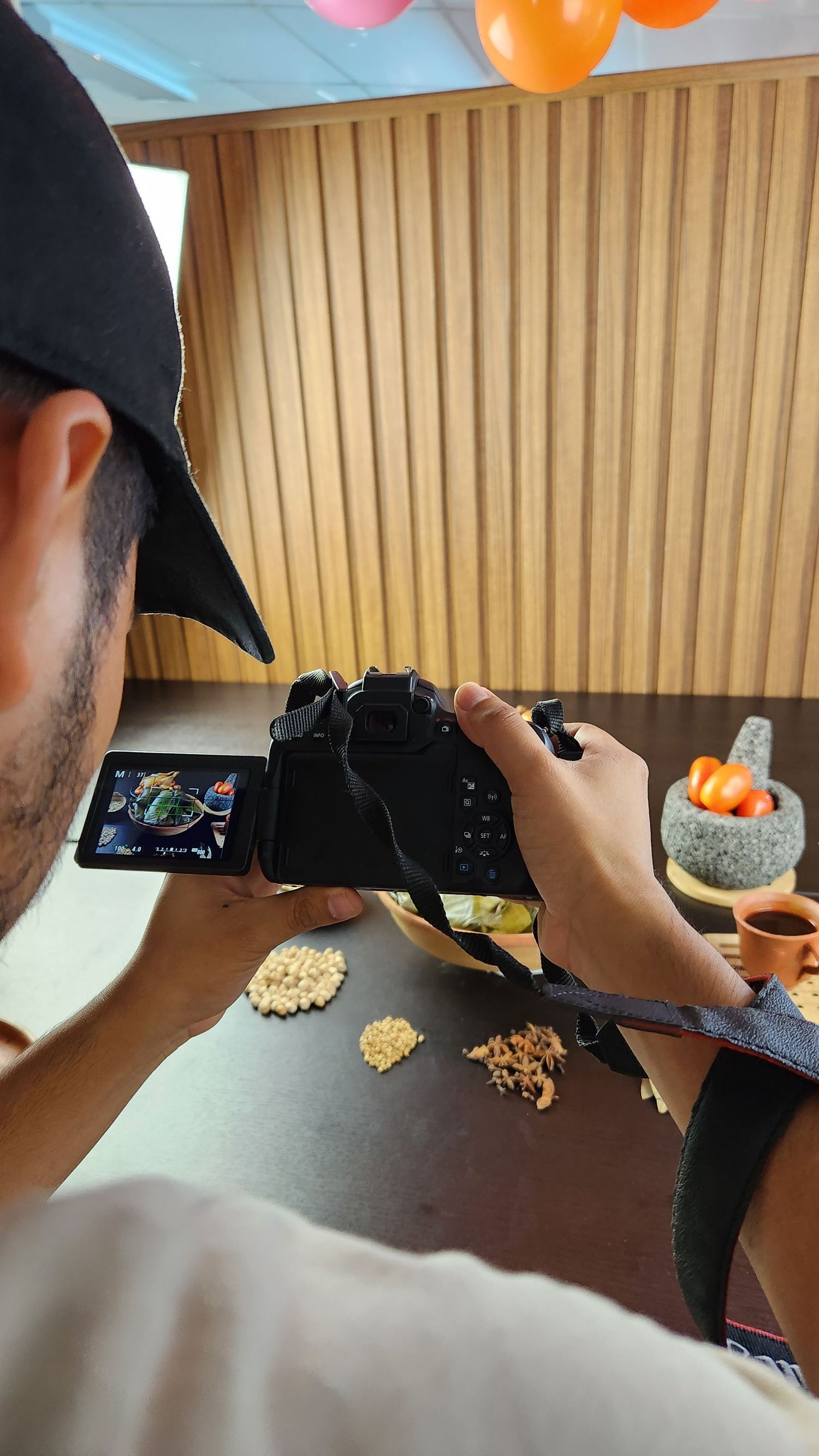 Photographer taking food photos with DSLR camera with balloons in background.