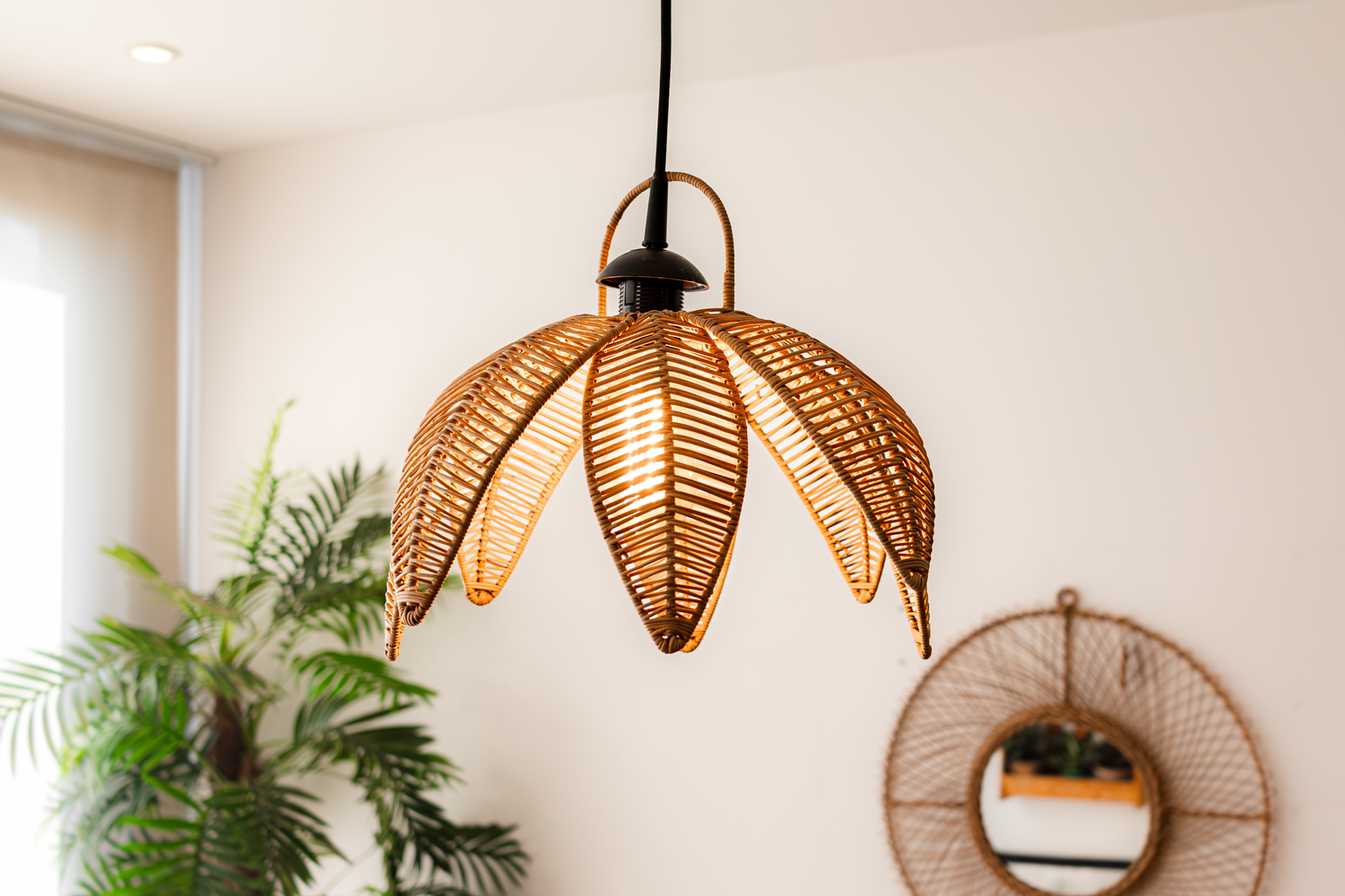 Boho-style woven rattan pendant light fixture with leaf design hanging from ceiling.