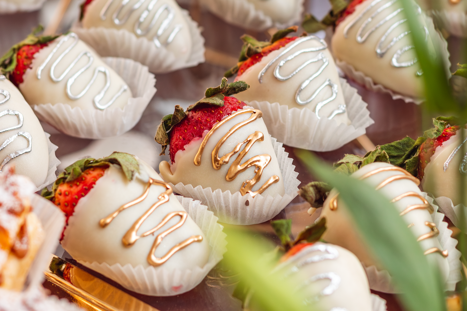 White chocolate covered strawberries decorated with drizzles arranged on a serving platter.