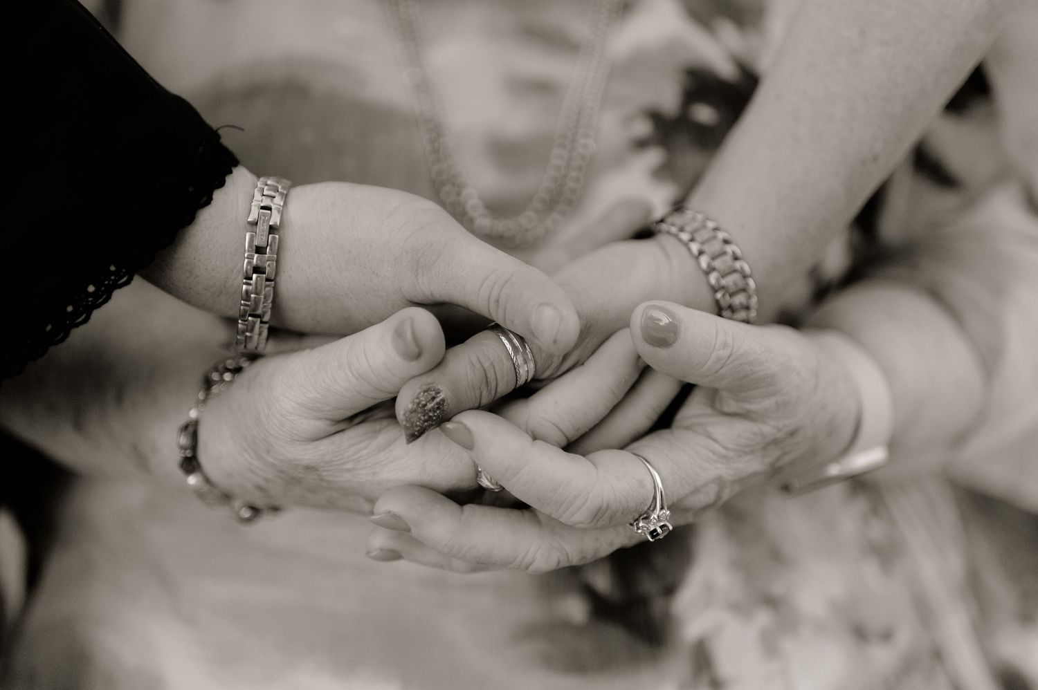 Close-up of hands with rings and bracelets touching in a tender moment.