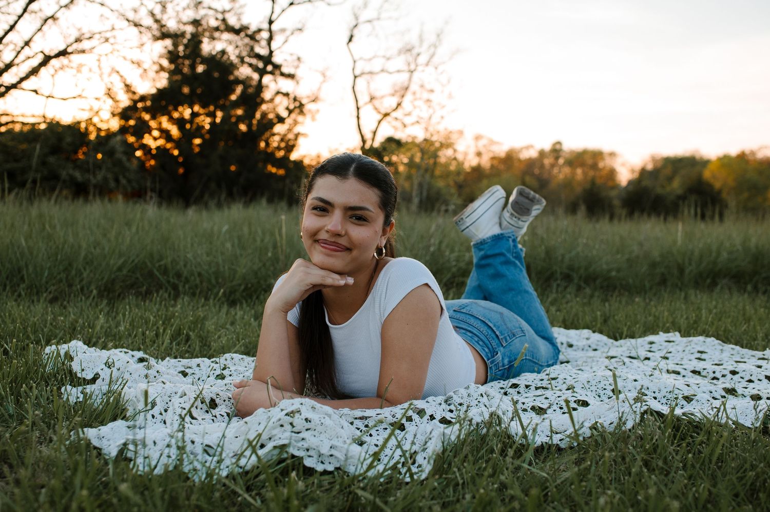 A couple lying in a field of white wildflowers during golden hour sunset.