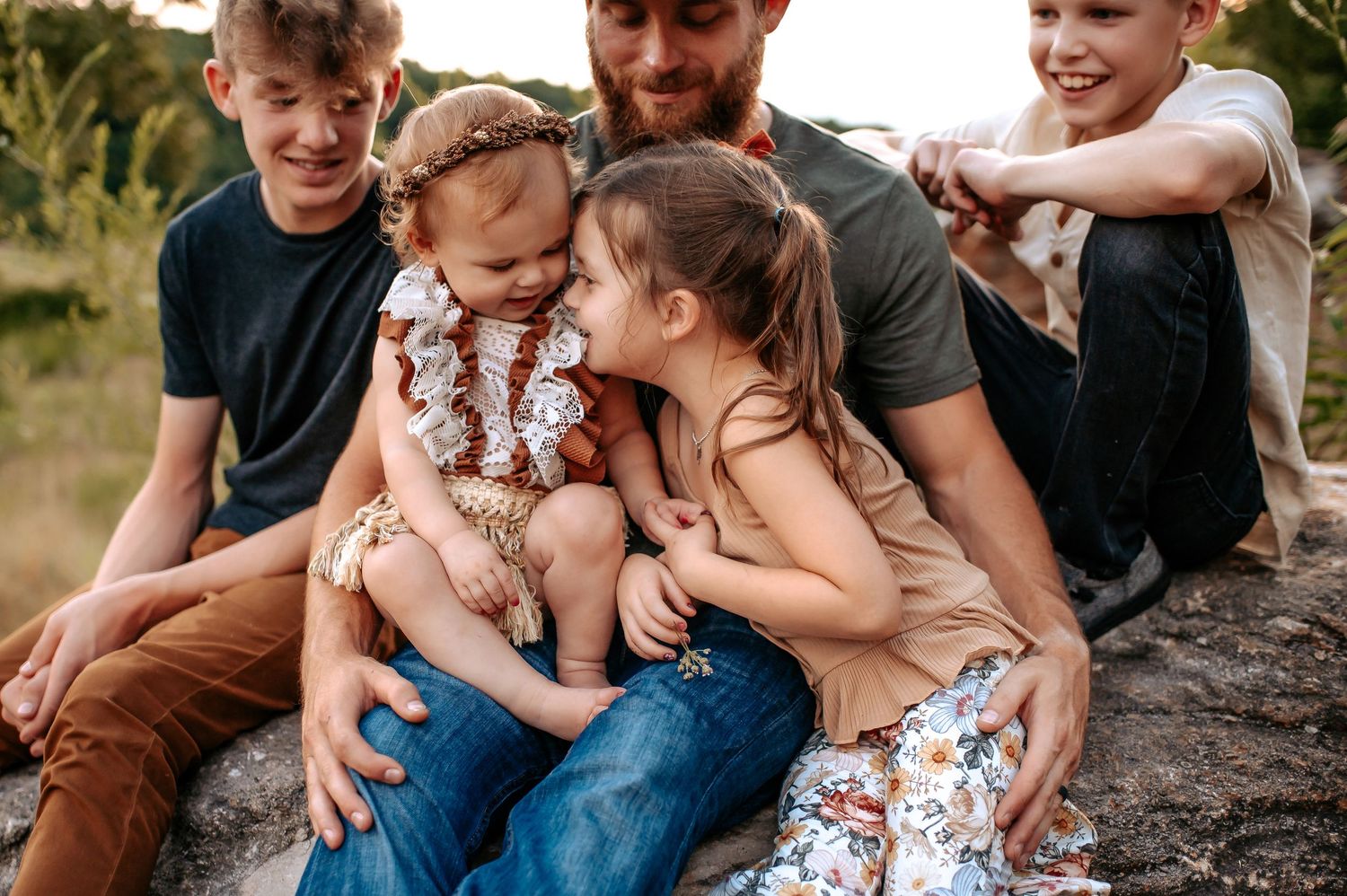 An intimate family moment shared while sitting on a rocky outcrop in nature.
