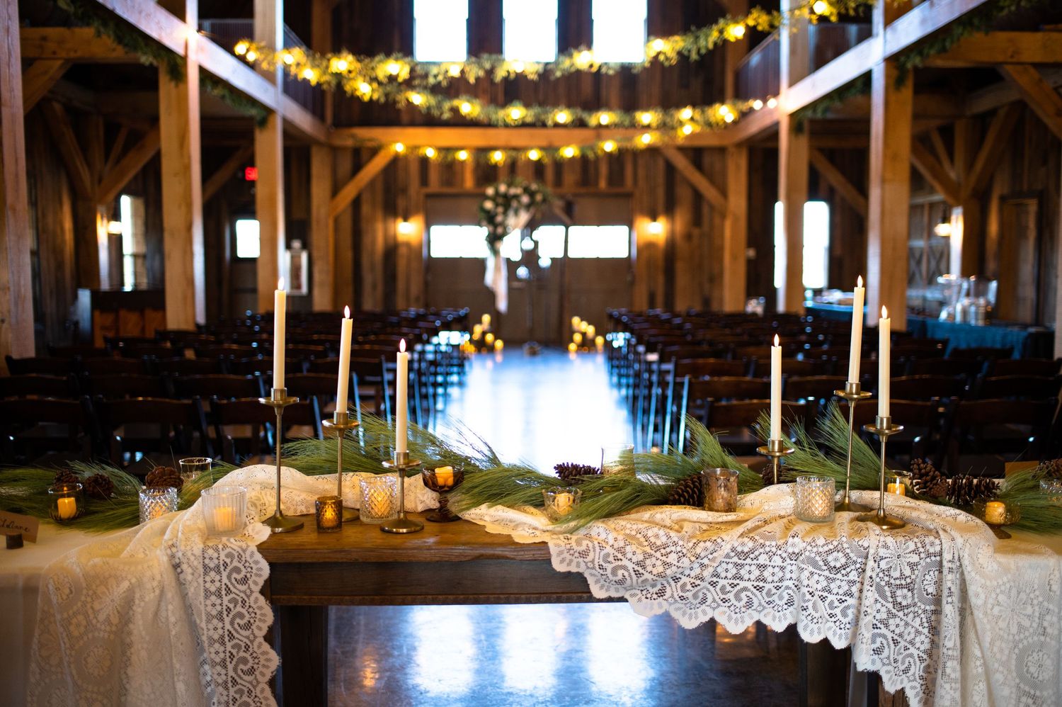 Rustic barn wedding venue with string lights and lace-covered reception tables at dusk.