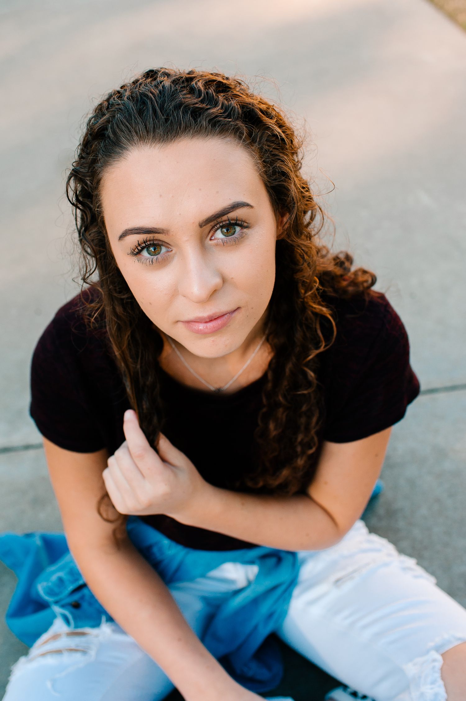 Portrait of someone with curly dark hair wearing a black top against a light background.