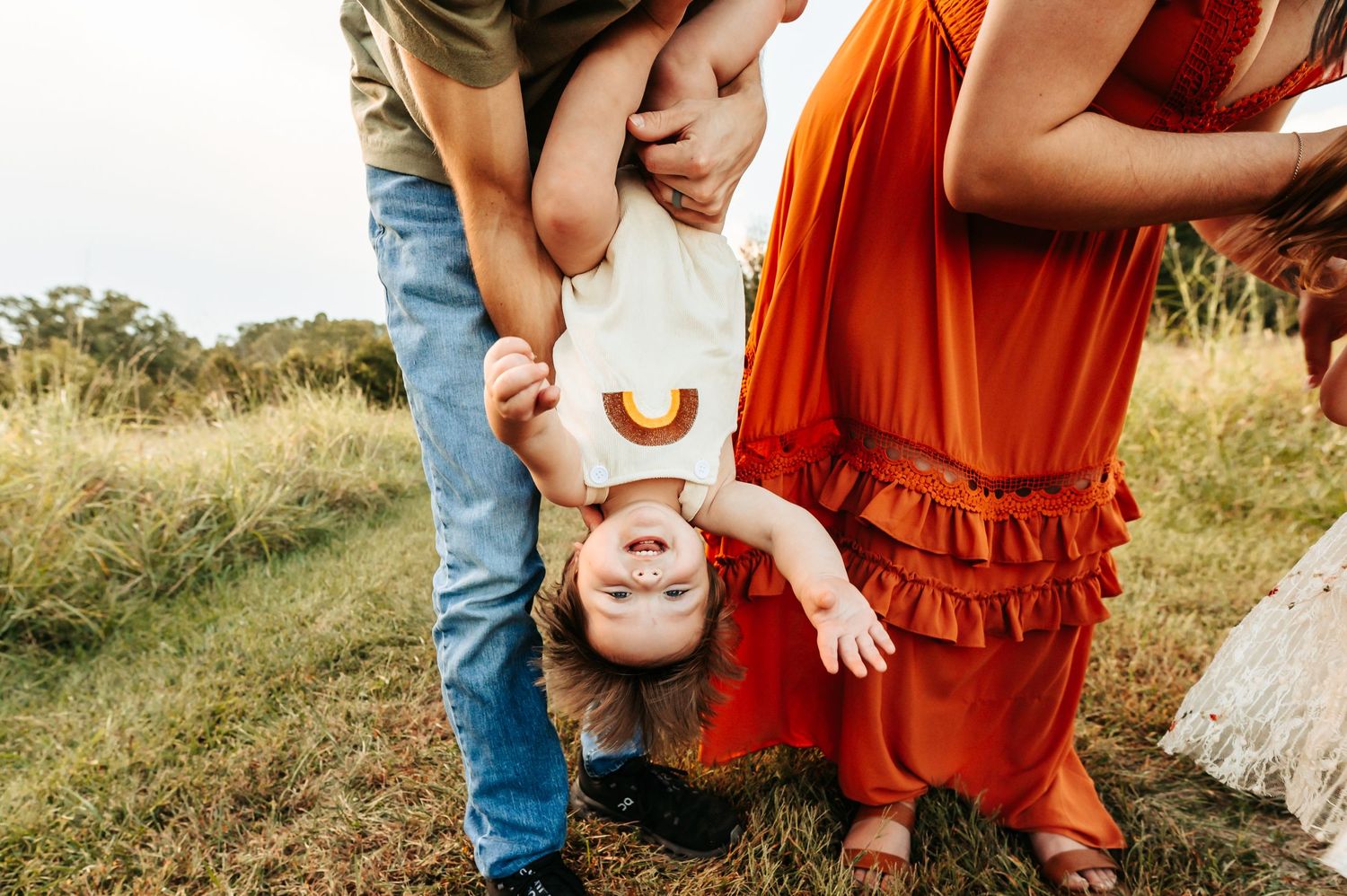 Playful outdoor family moment captured in golden field during sunset.