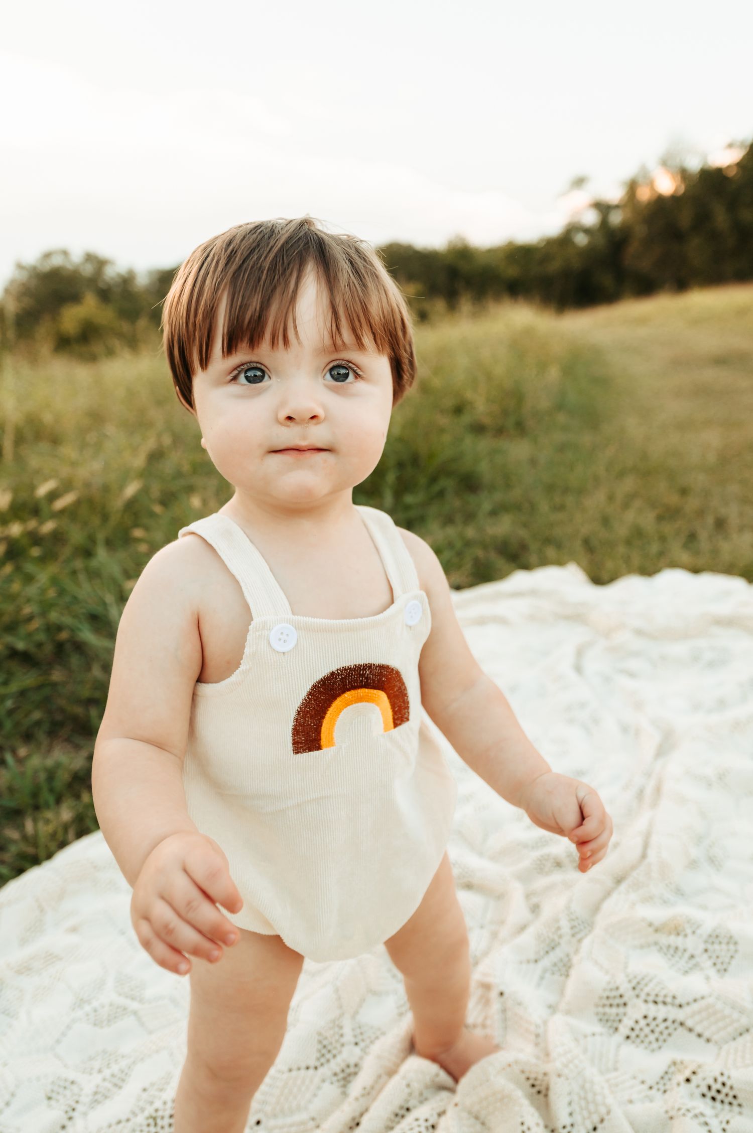 Sweet portrait on white blanket featuring rainbow motif apparel.