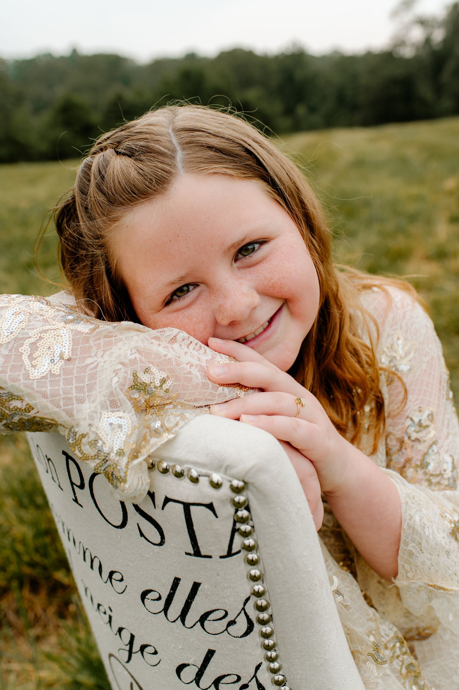 Portrait in a sunny field with vintage-style decorative pillow.