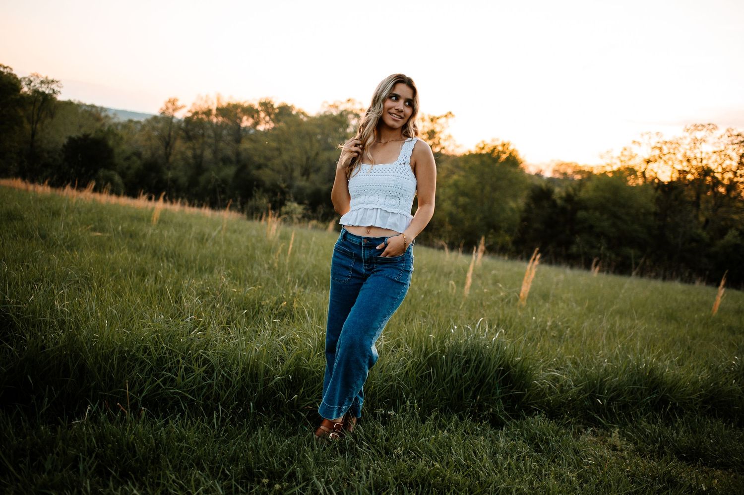 Golden sunset illuminates a grassy field with a figure silhouetted against the warm evening sky.