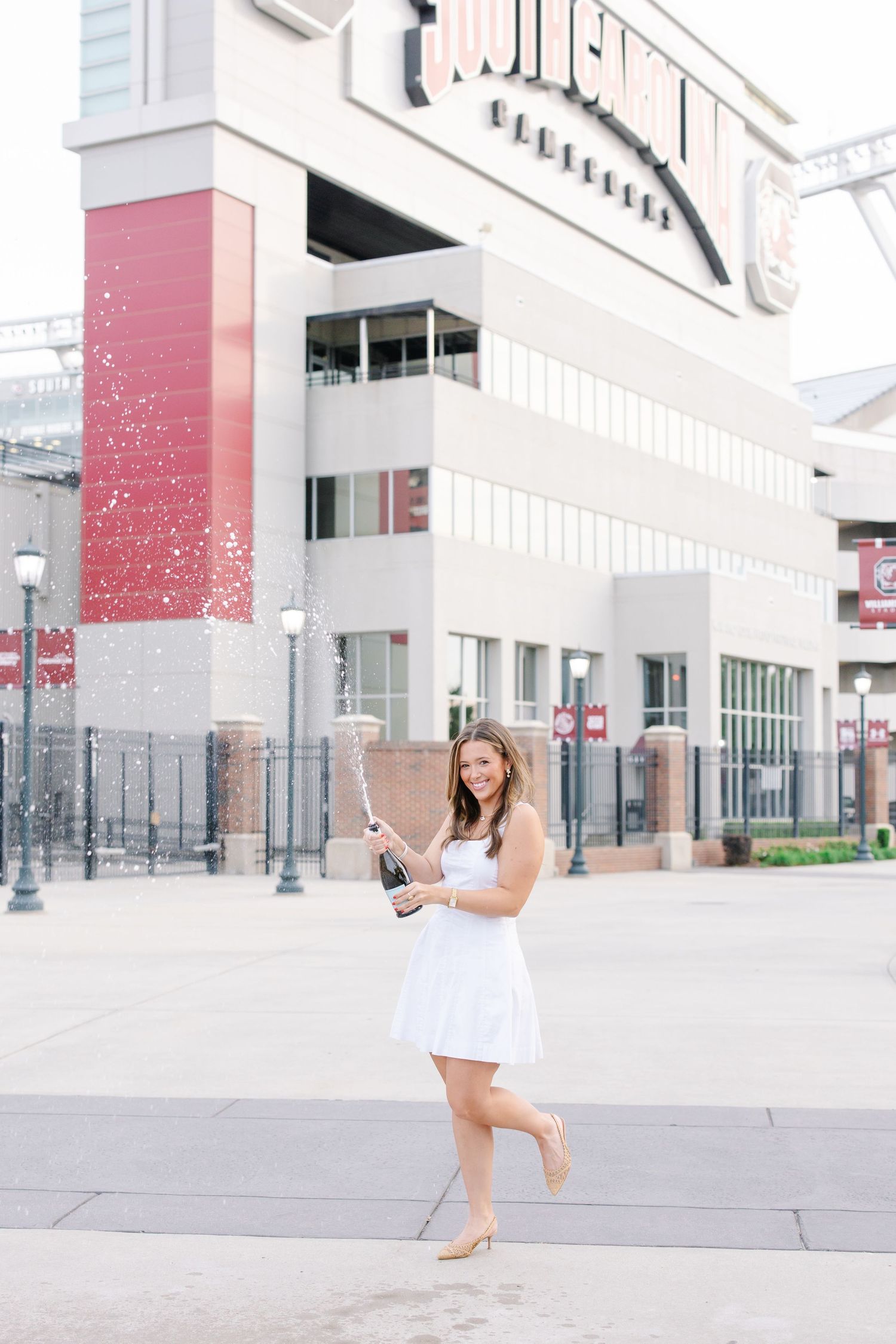 White-dressed figure poses playfully outside modern urban building.