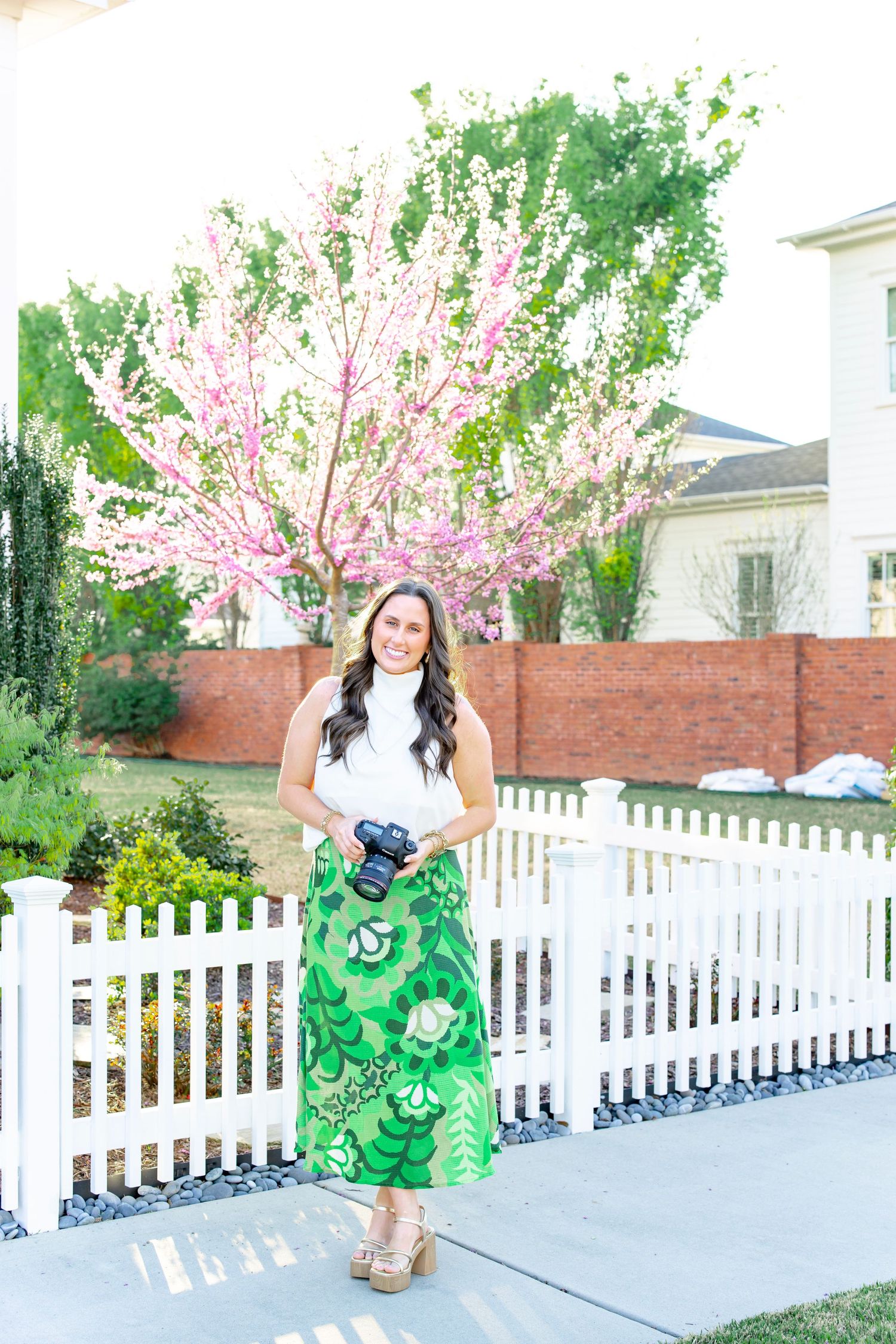 Spring portrait with blooming cherry tree and white picket fence in a residential garden setting.