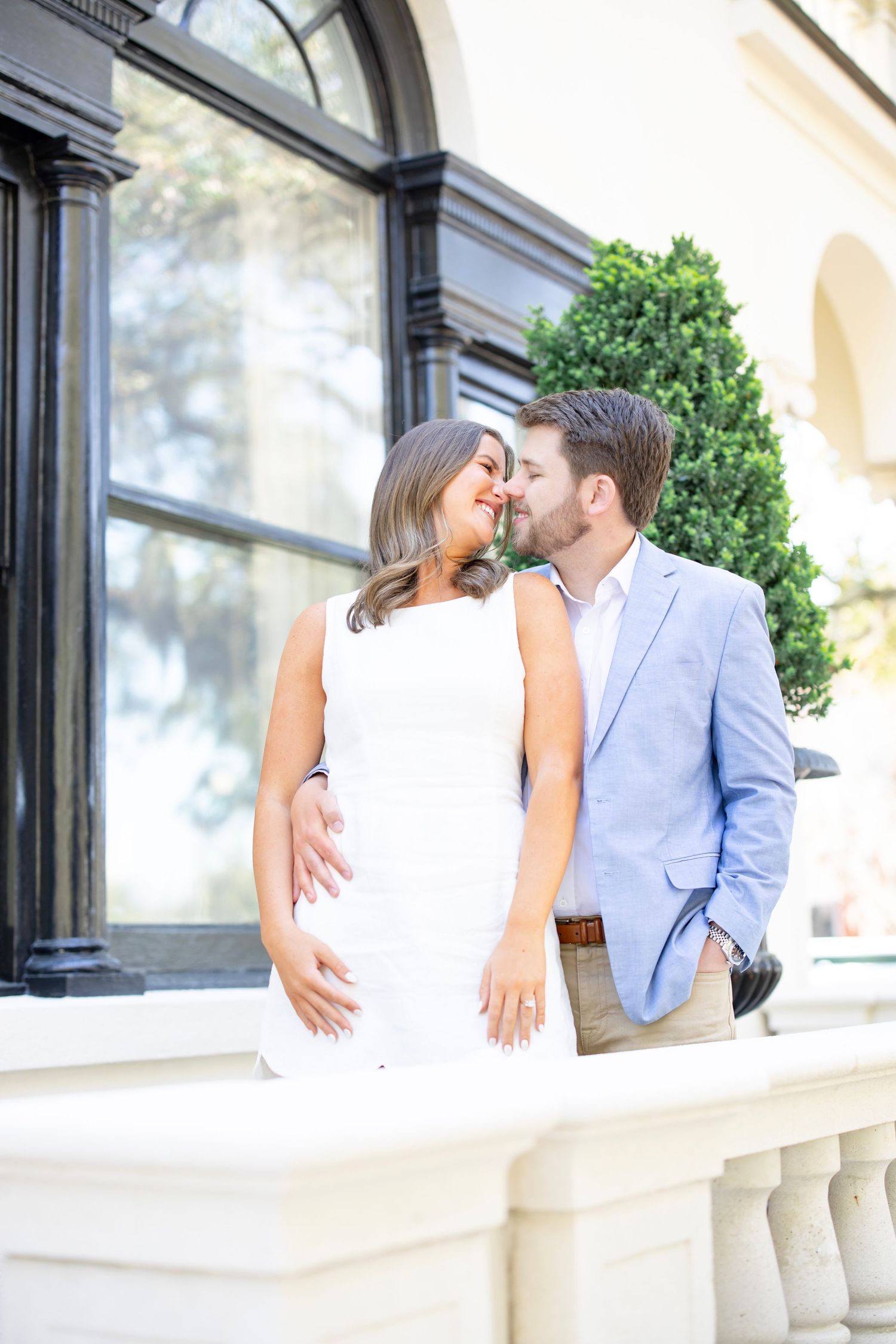A couple in coordinating blue and white outfits sharing an intimate moment near an ornate building facade.