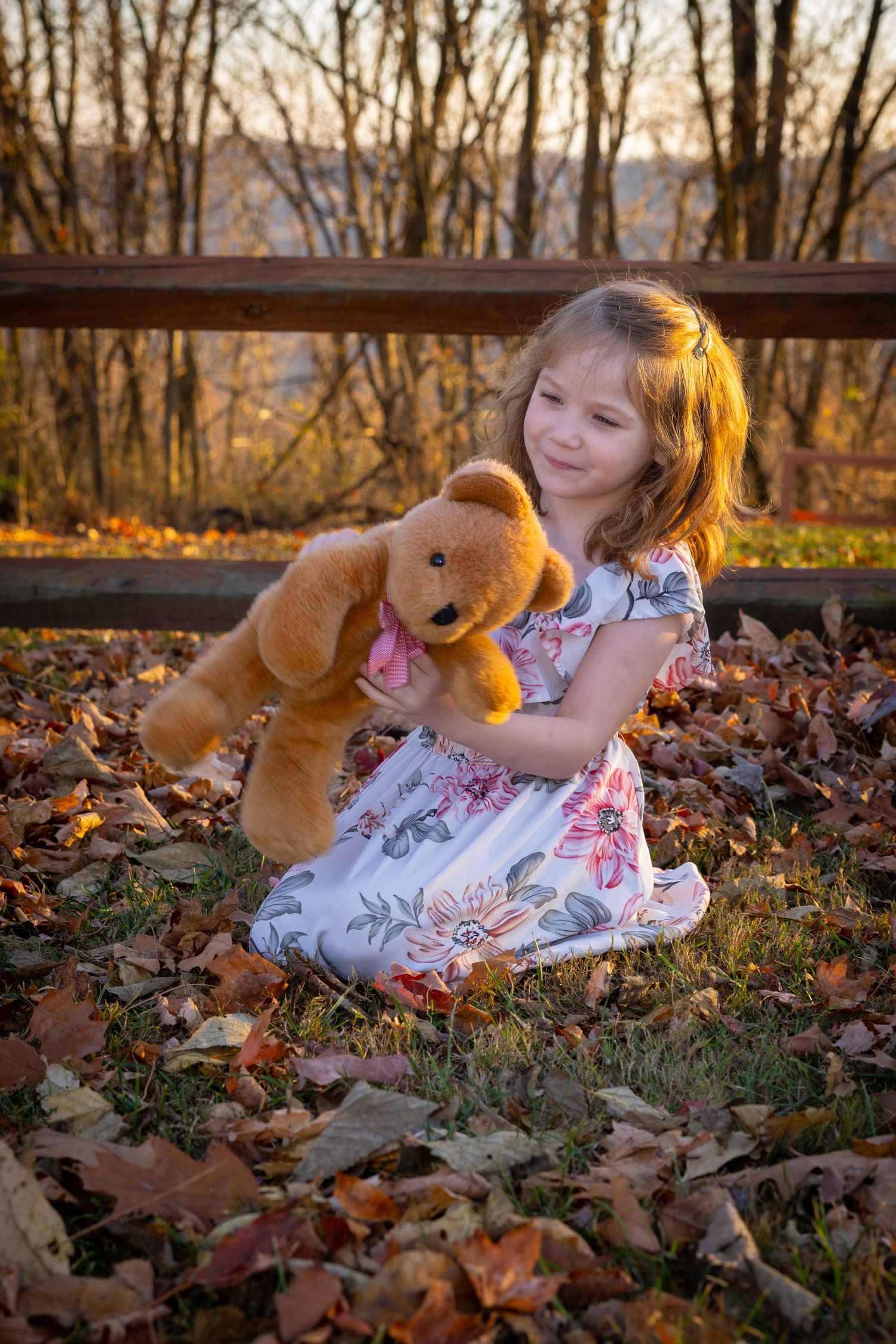 Child and golden retriever puppy play together in fallen autumn leaves at sunset.