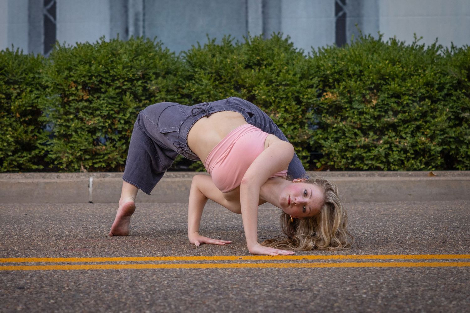 Dance movements performed on pavement with greenery in background.
