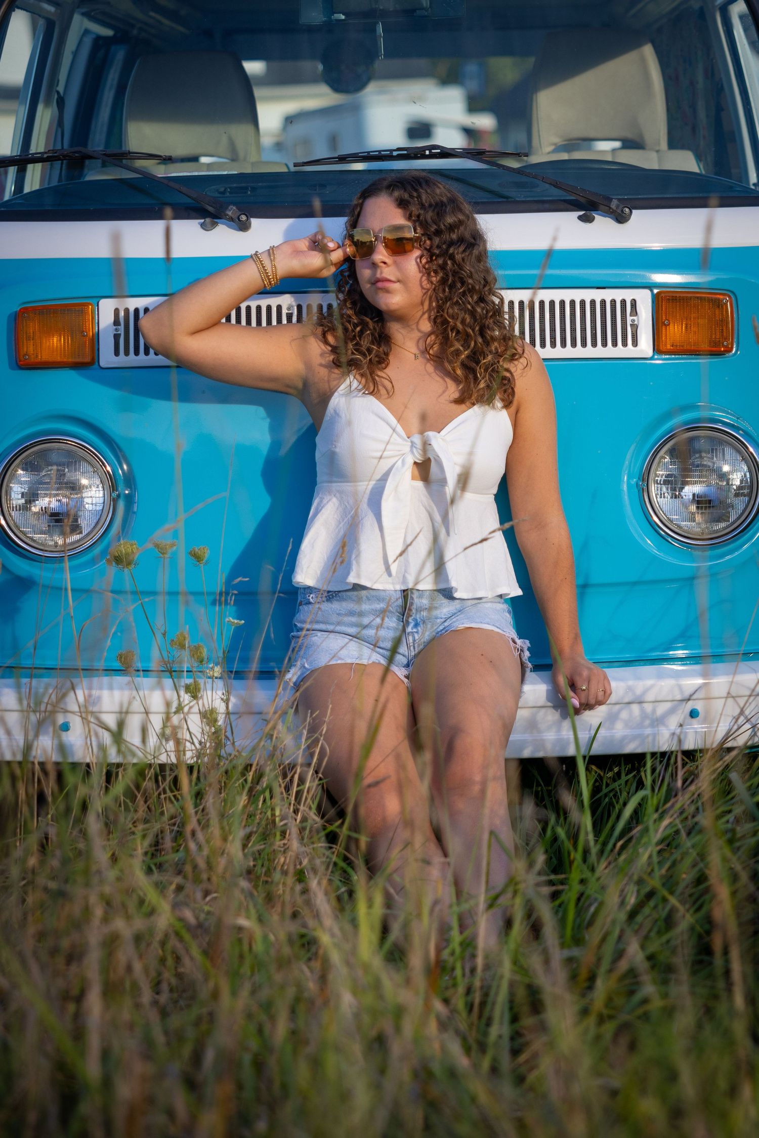 Vintage blue van serves as backdrop for summer lifestyle photoshoot in tall grass.