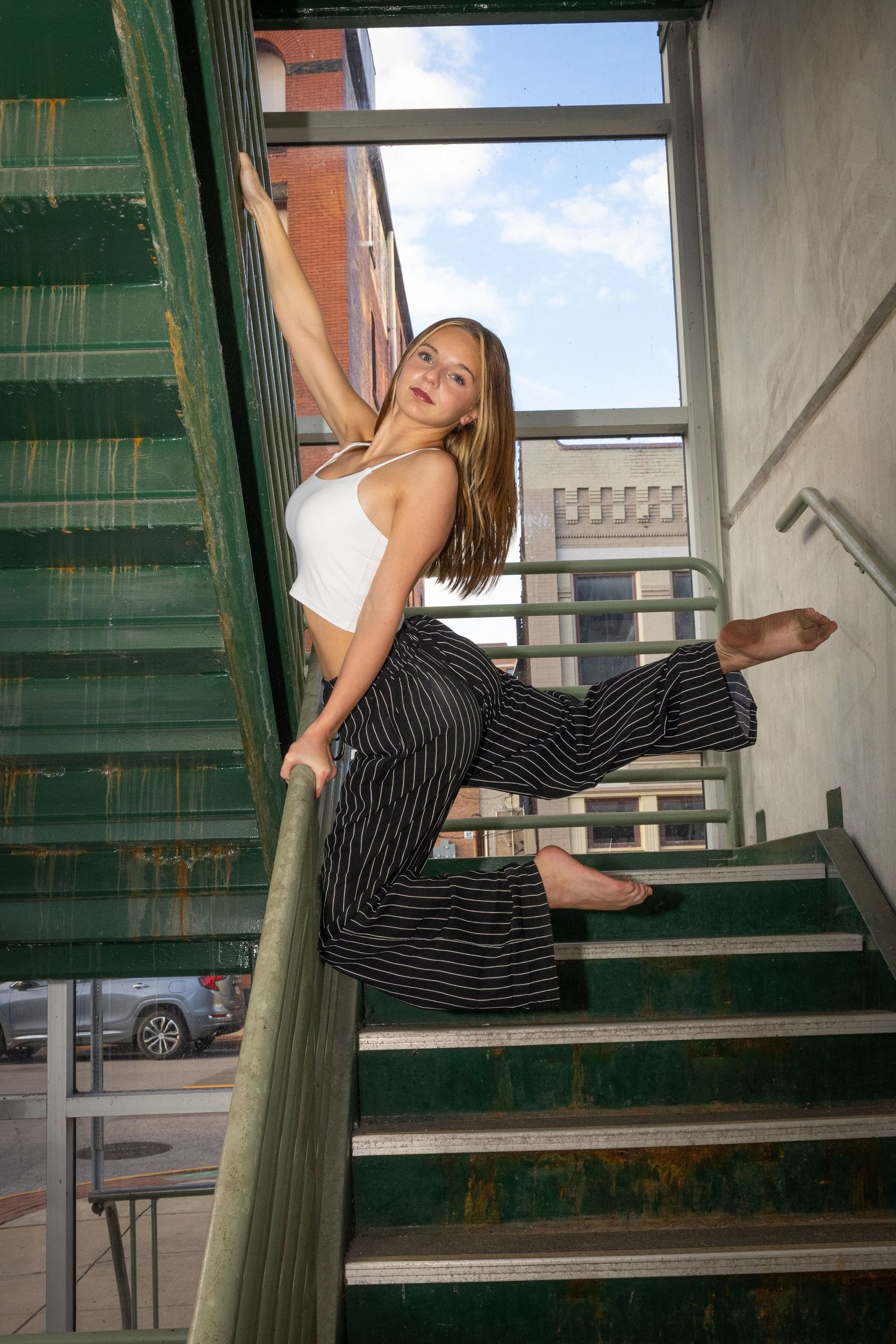 Dance poses performed on green stairwell with window lighting.