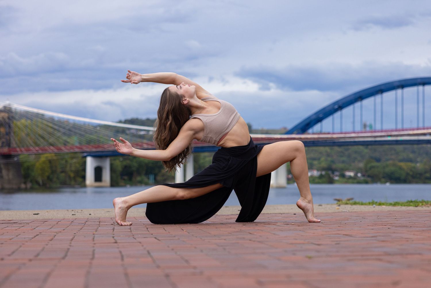 Dance poses performed outdoors against scenic mountain and bridge backdrop.