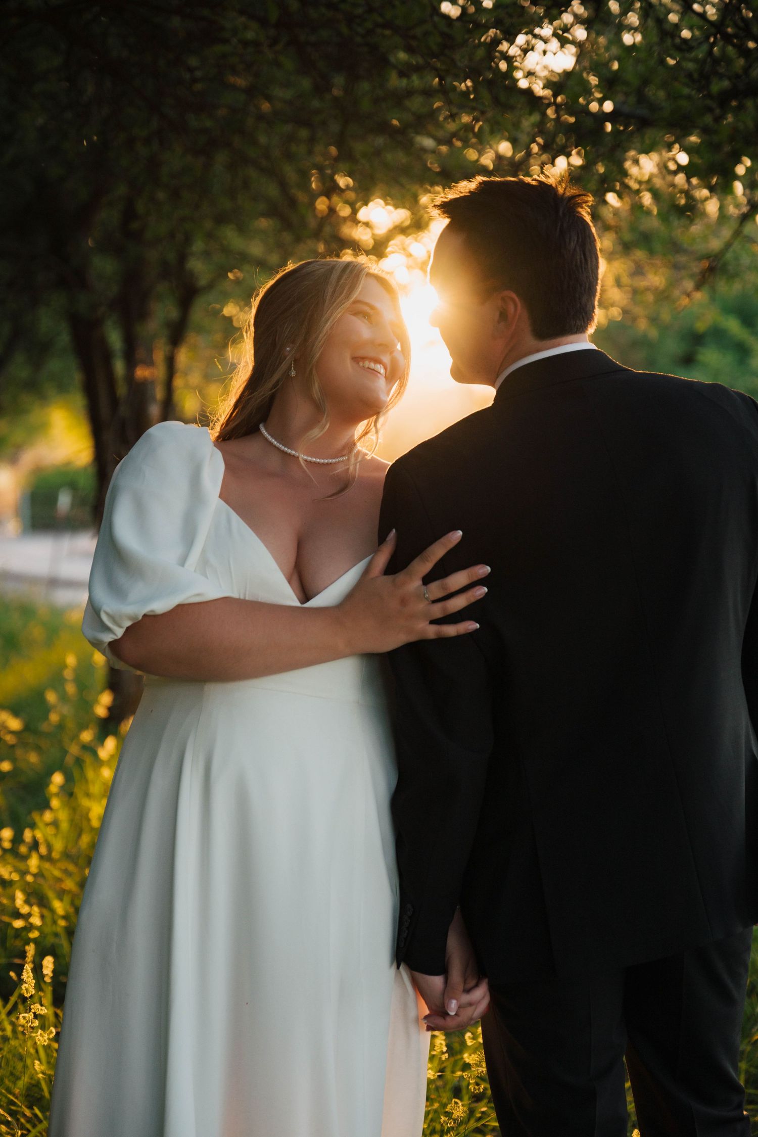 Newlywed couple sharing an intimate moment in a sunlit garden during golden hour.