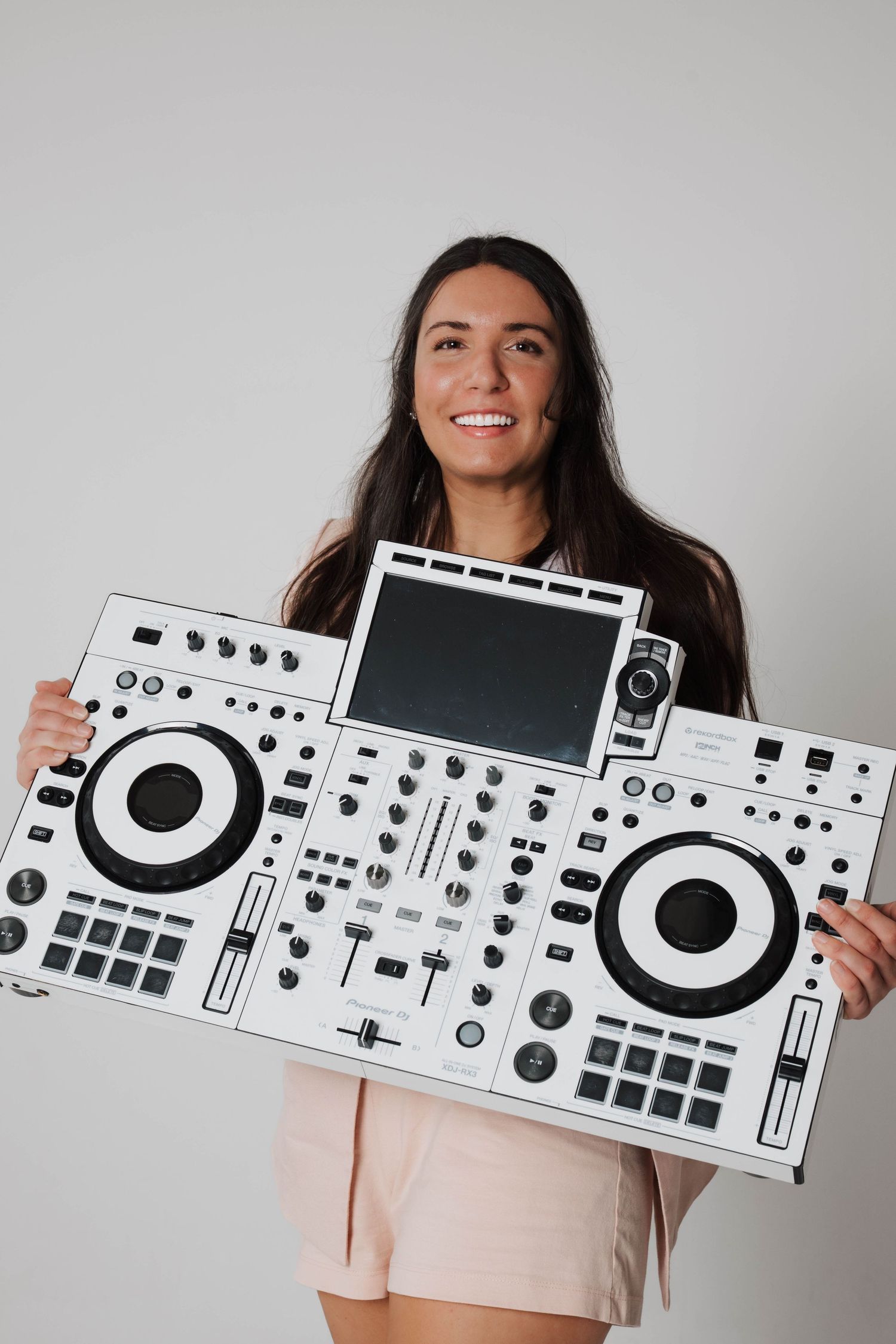 Someone holding up a decorative white DJ controller decal against a light gray background with a cheerful expression.