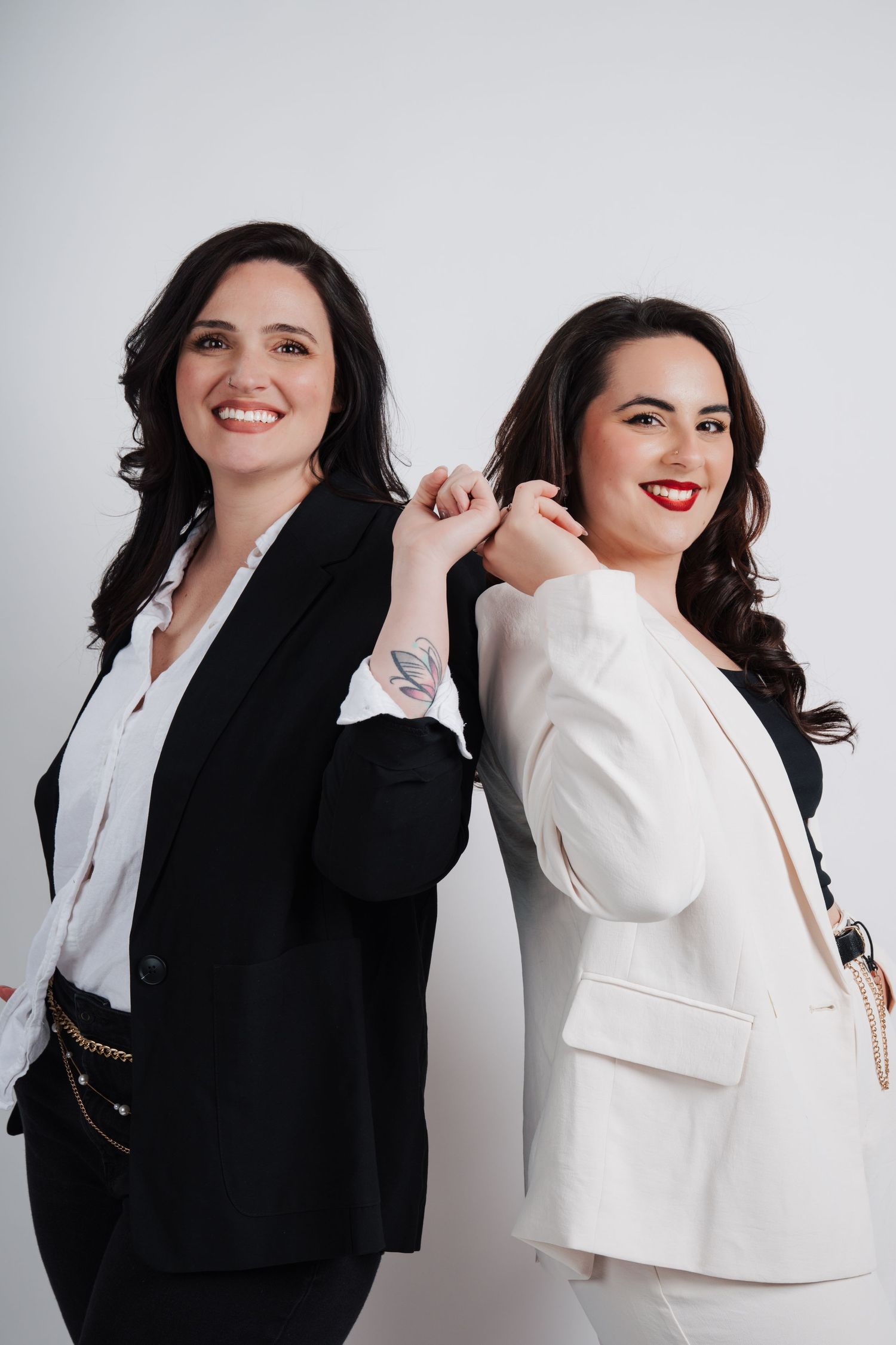 Professional women in contrasting black and white blazers pose together.