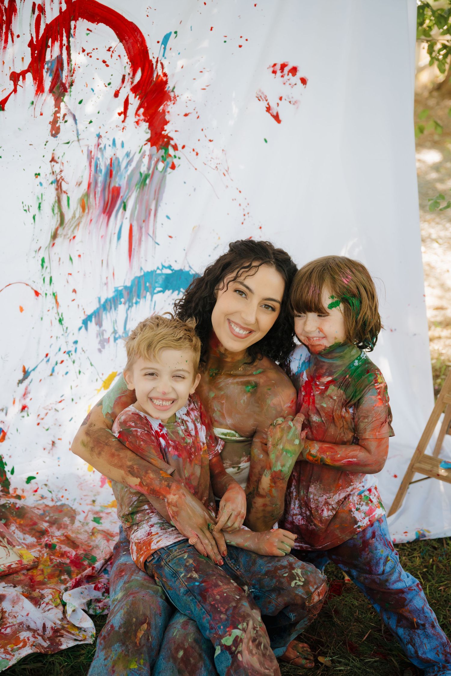 A colorful paint splatter photoshoot with children against a white backdrop.